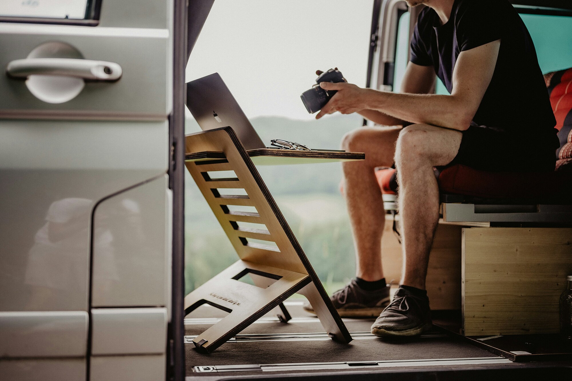 Arbeitsmodell Digital Nomad: im Homeoffice auf Reisen Ein Fotograf betrachtet im Wohnmobil Bilder am Laptop.