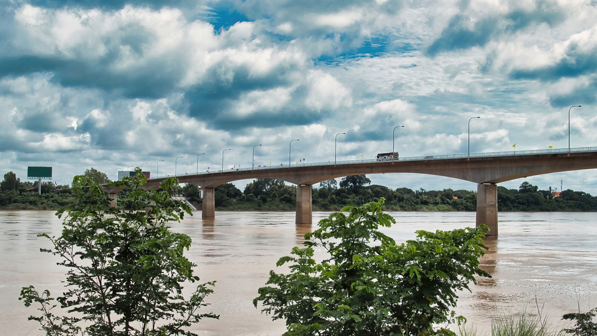 Die Thai-Lao Friendship Bridge, die Laos und Thailand verbindet. Sie ist eine große Betonbrücke mit mehreren Fahrspuren, die über einen breiten Fluss führt.