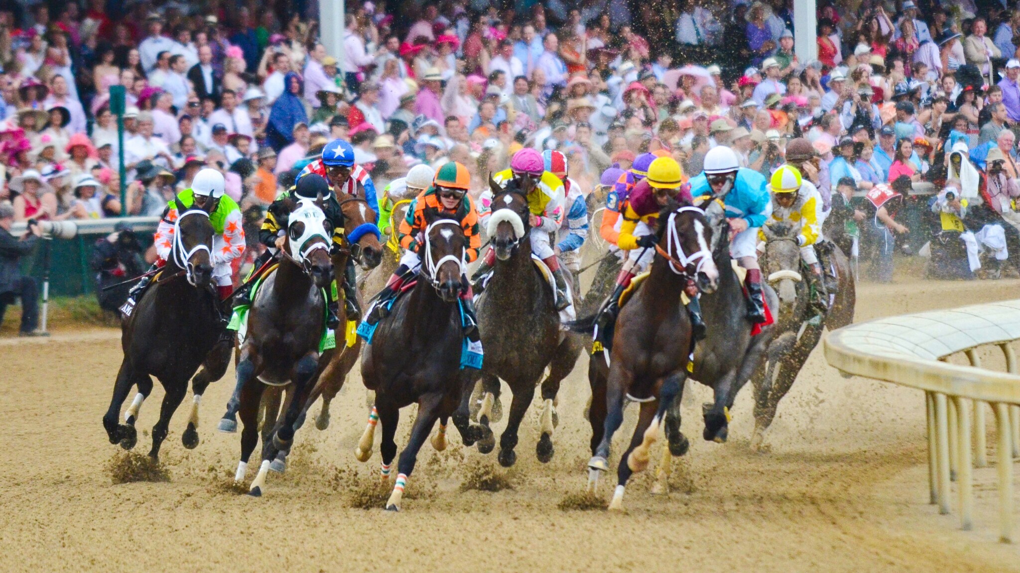 Mehrere Jockeys reiten Pferde in einem Pferderennen auf der Rennbahn Churchill Downs vor einer großen Zuschauertribüne.