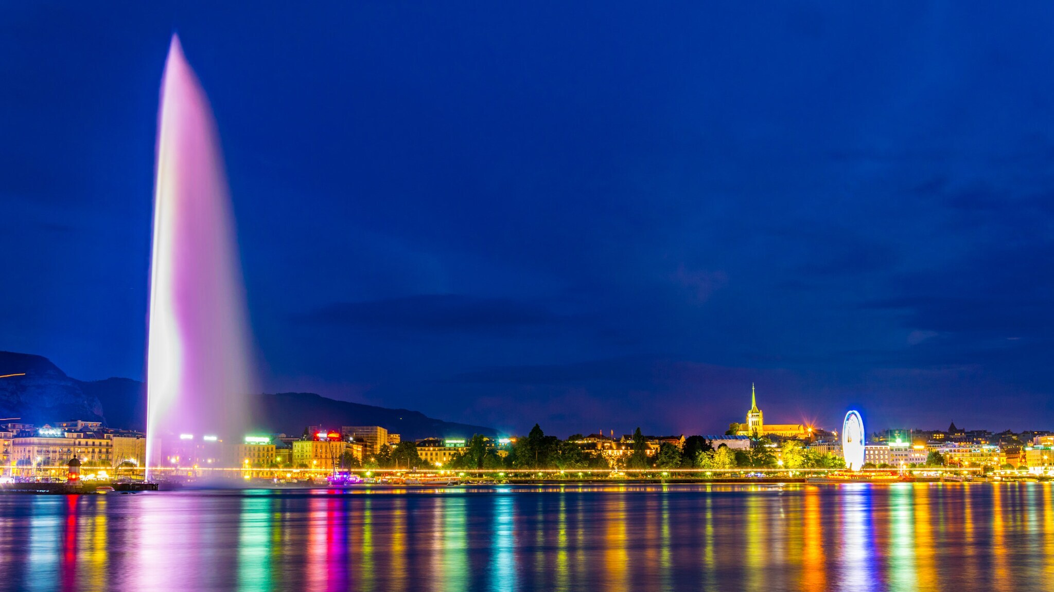 Wasserfontäne in Genf bei Nacht und bunt angeleuchtet.