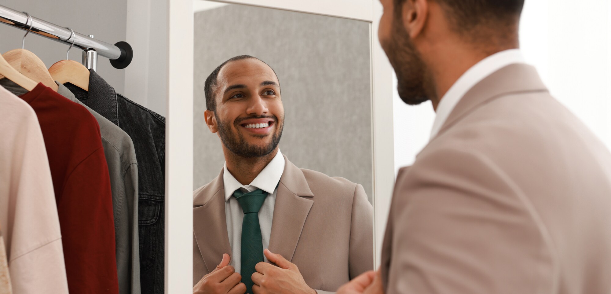 Nachhaltig, minimalistisch, stylish: Die Capsule Wardrobe fürs Business Ein Geschäftsmann im Anzug betrachtet sich im Spiegel.