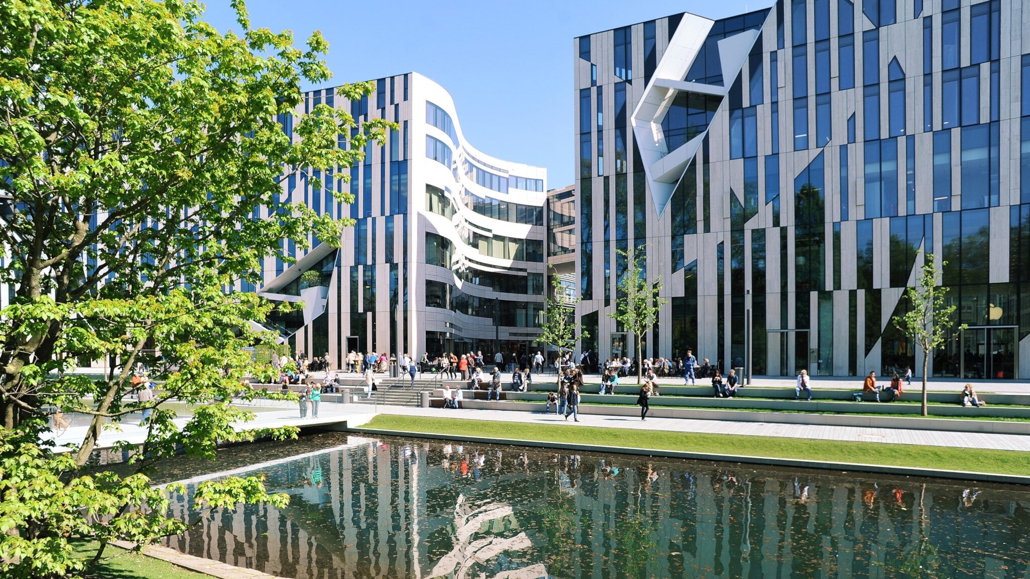 Moderne Bürogebäude mit Glasfassaden am Wasserbecken im Kö-Bogen Düsseldorf, Menschen sitzen und gehen auf der Promenade Moderne Bürogebäude mit Glasfassaden am Wasserbecken im Kö-Bogen Düsseldorf, Menschen sitzen und gehen auf der Promenade