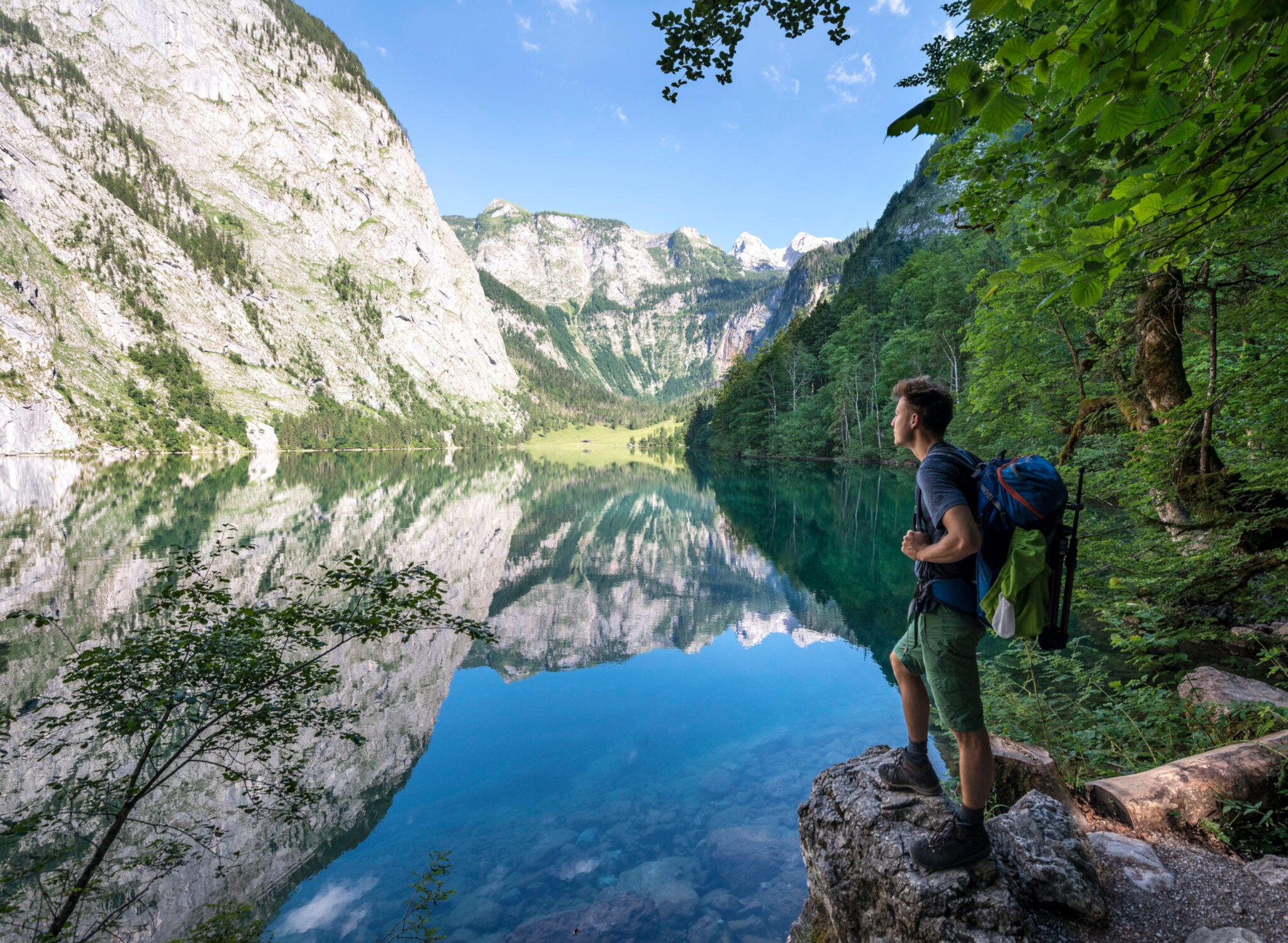Ein Mann mit Rucksack und in Wanderoutfit blickt auf den Königssee.