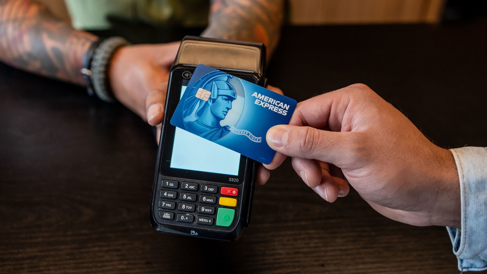 Kontaktlose Zahlung mit einer blauem American Express Kreditkarte an einem Kartenlesegerät. Kontaktlose Zahlung mit einer blauem American Express Kreditkarte an einem Kartenlesegerät.