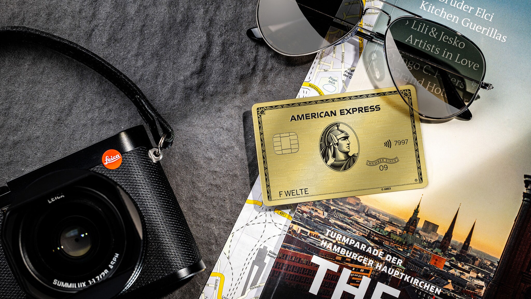 Eine goldene Kreditkarte liegt neben einer Kamera auf einem Reiseführer. Eine goldene Kreditkarte liegt neben einer Kamera auf einem Reiseführer.