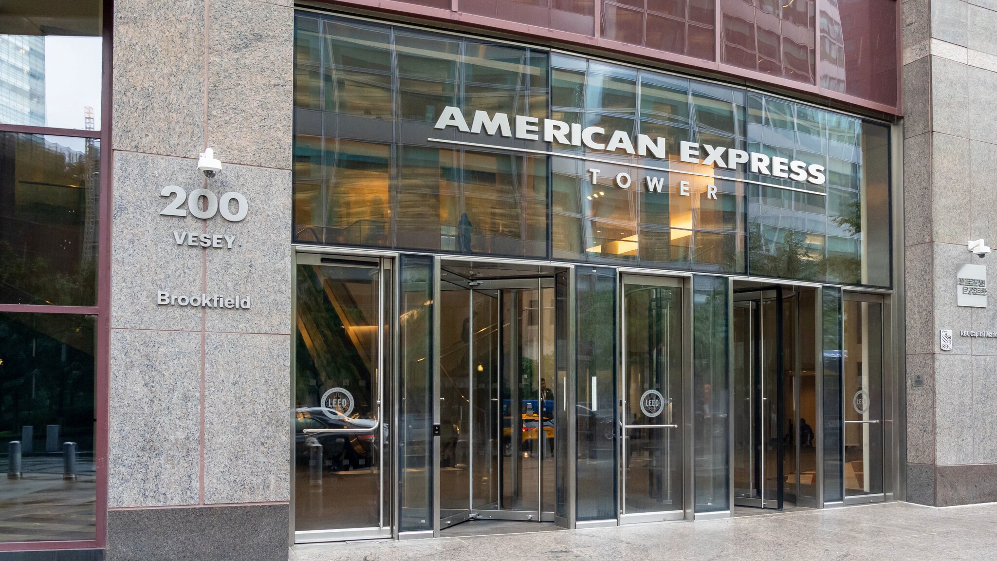 Eingangsbereich mit Glastüren zu einem Gebäude mit der Aufschrift American Express Tower.