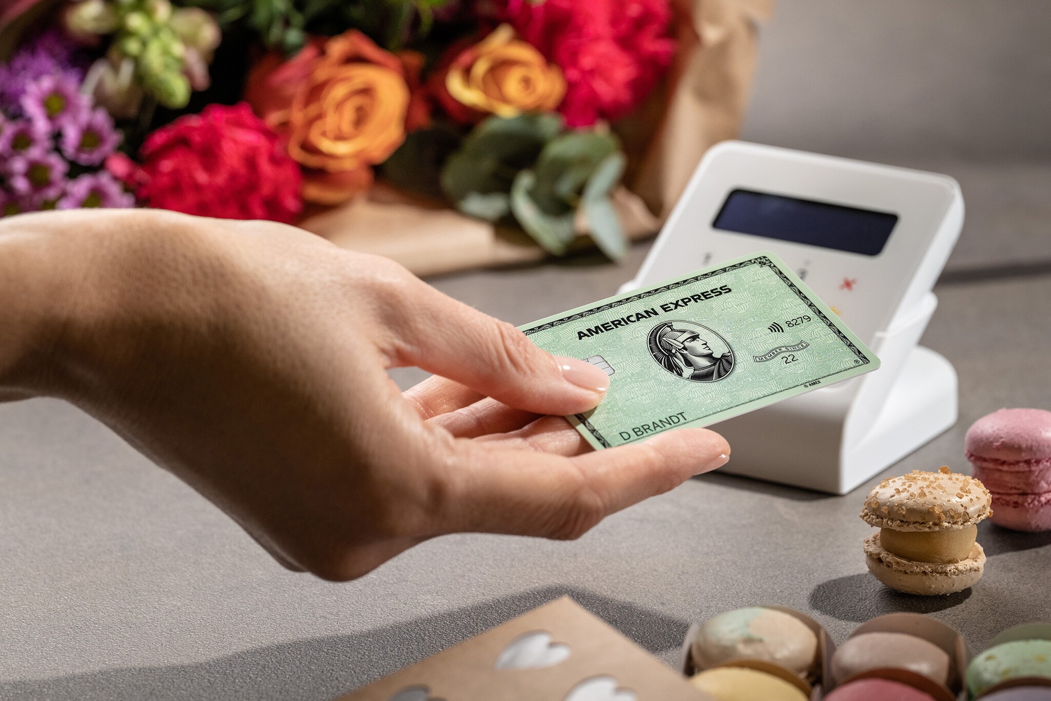 Eine Kundin bezahlt kontaktlos mit der American Express Card an einem Kartenlesegerät