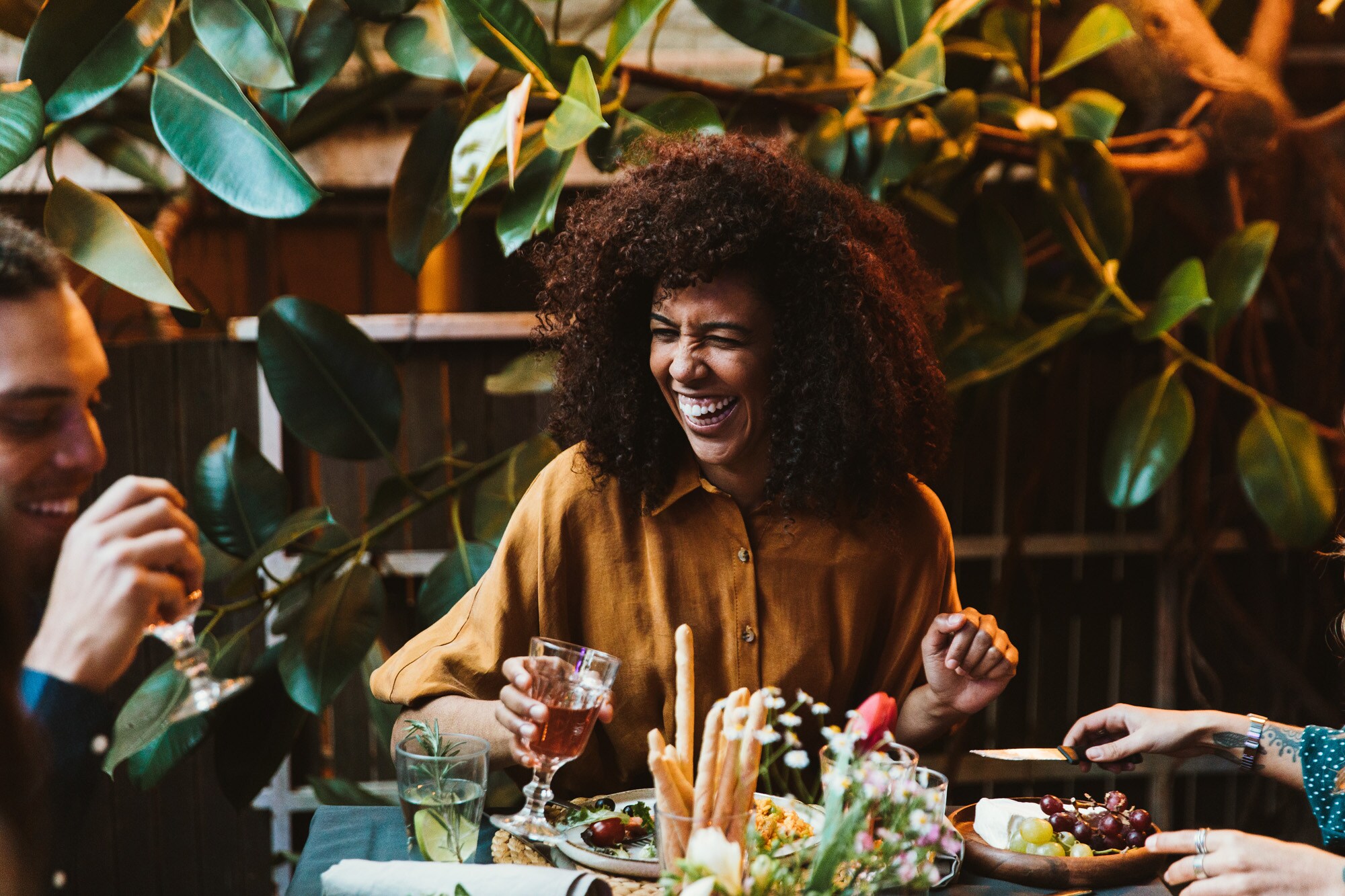 Eine lachende Frau an einem Restauranttisch in Gesellschaft von Freunden