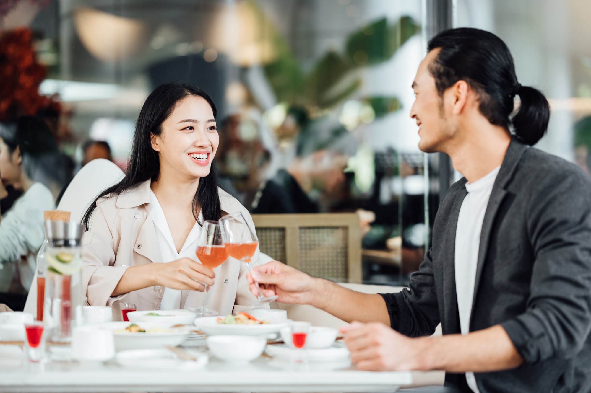 Eine Frau und ein Mann sitzen in einem Restaurant und stoßen an.
