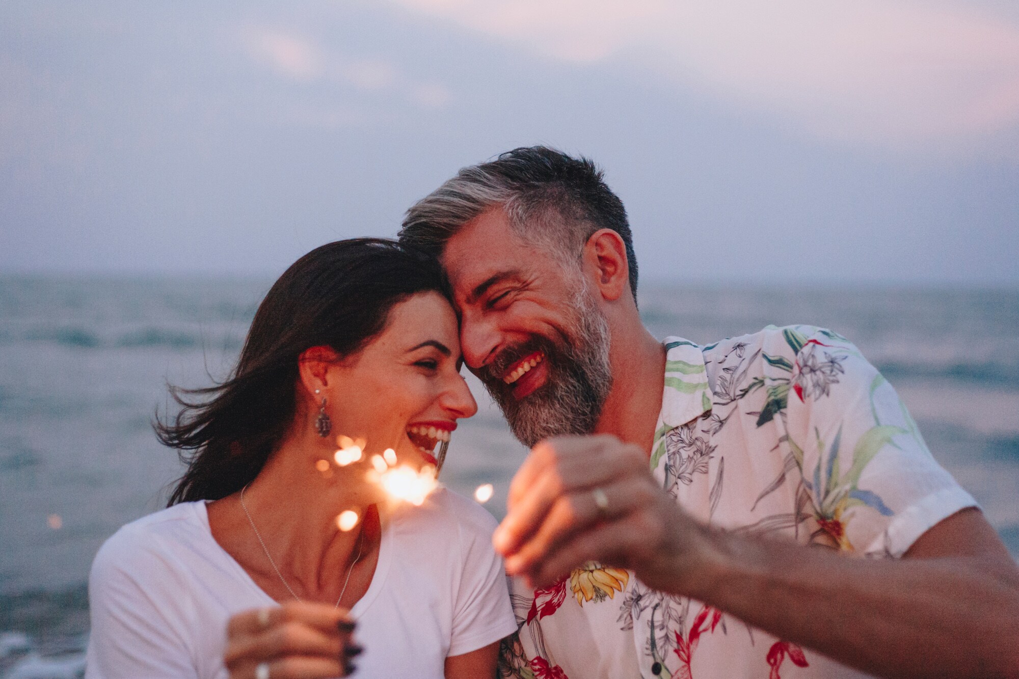 Eine Frau und ein Mann mit Wunderkerzen in der Hand am Strand