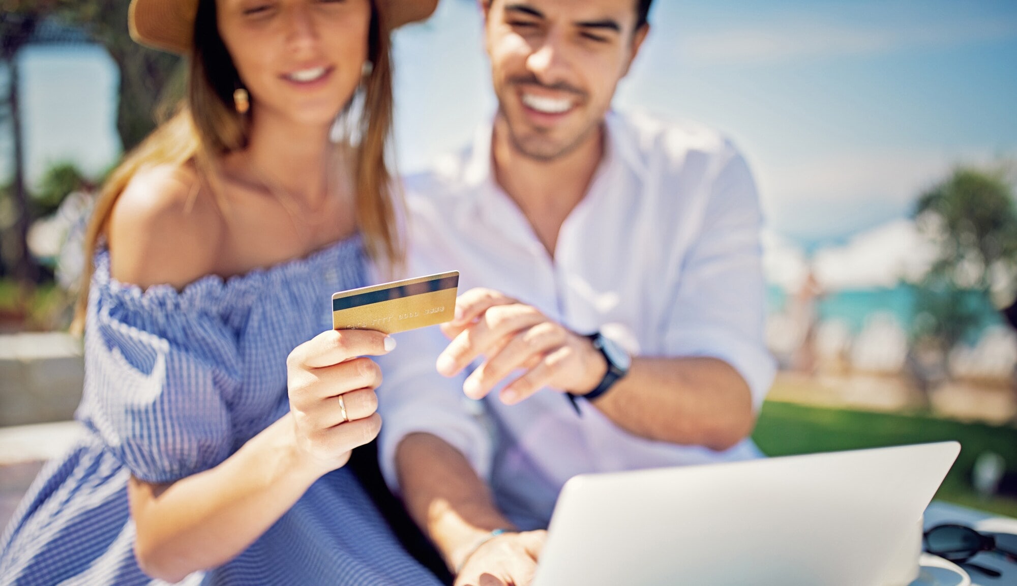 Ein Paar sitzt vor dem Laptop und schaut auf eine goldene Kreditkarte