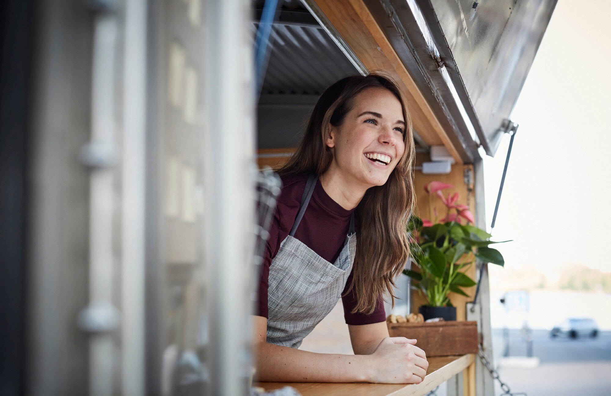 Eine lachende Frau schaut aus einem Food-Truck