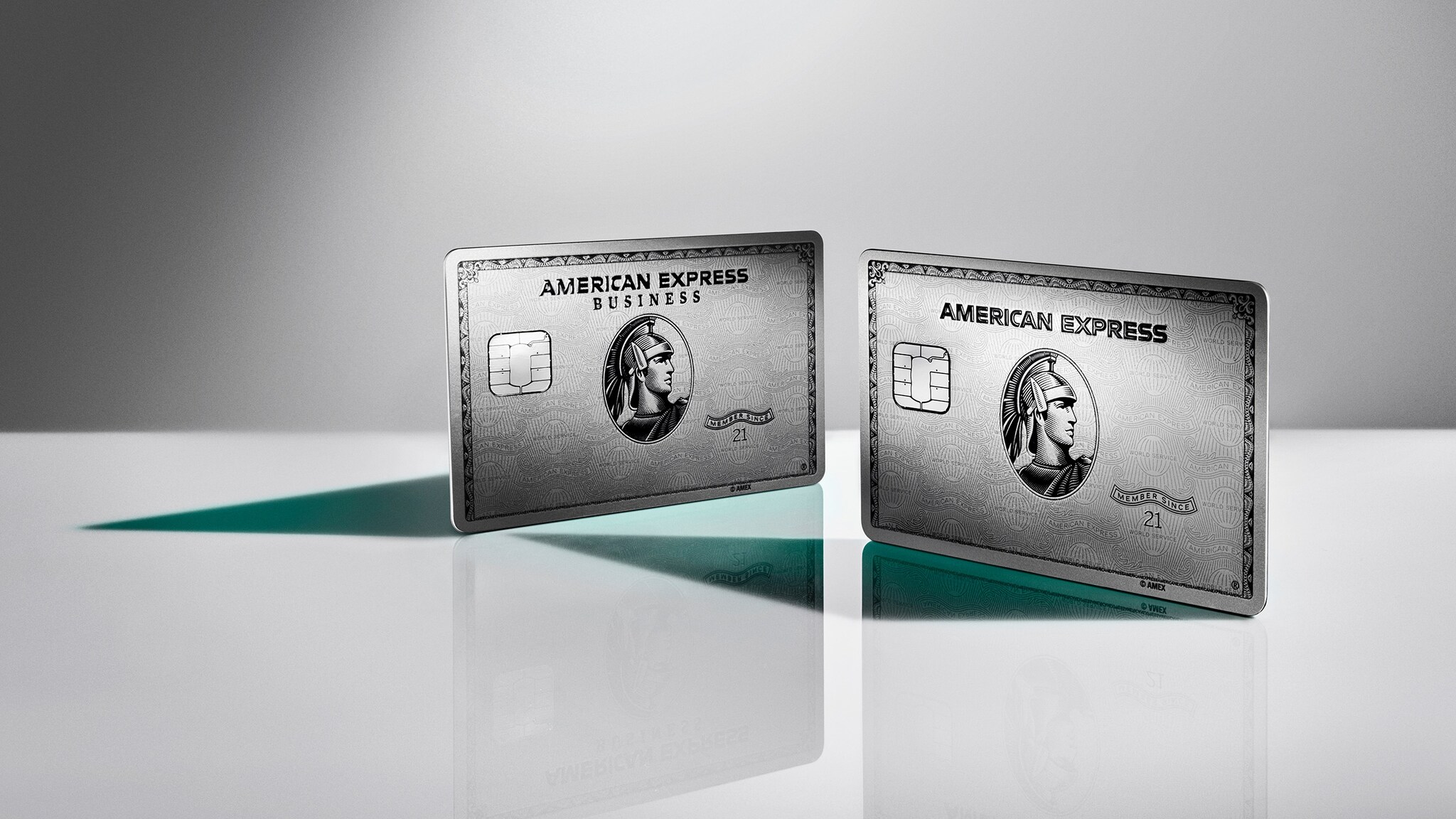 Studioaufnahme einer aufgestellten silbernen American Express Business Kreditkarte neben einer aufgestellten silbernen American Express Kreditkarte auf einer weißen Spiegelfläche vor grauem Hintergrund. Studioaufnahme einer aufgestellten silbernen American Express Business Kreditkarte neben einer aufgestellten silbernen American Express Kreditkarte auf einer weißen Spiegelfläche vor grauem Hintergrund.