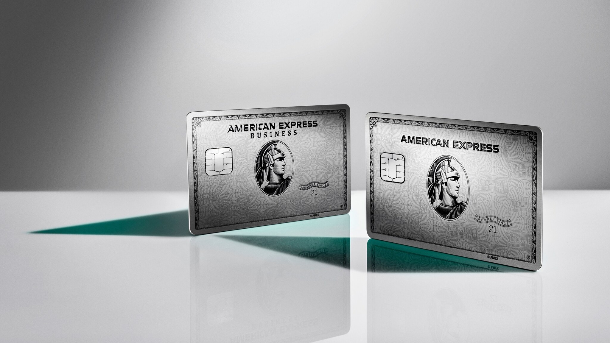 Die American Express Business Platinum Card neben der Platinum Plus Card, aufgestellt auf einer glänzenden Fläche vor grauem Hintergrund. Die American Express Business Platinum Card neben der Platinum Plus Card, aufgestellt auf einer glänzenden Fläche vor grauem Hintergrund.