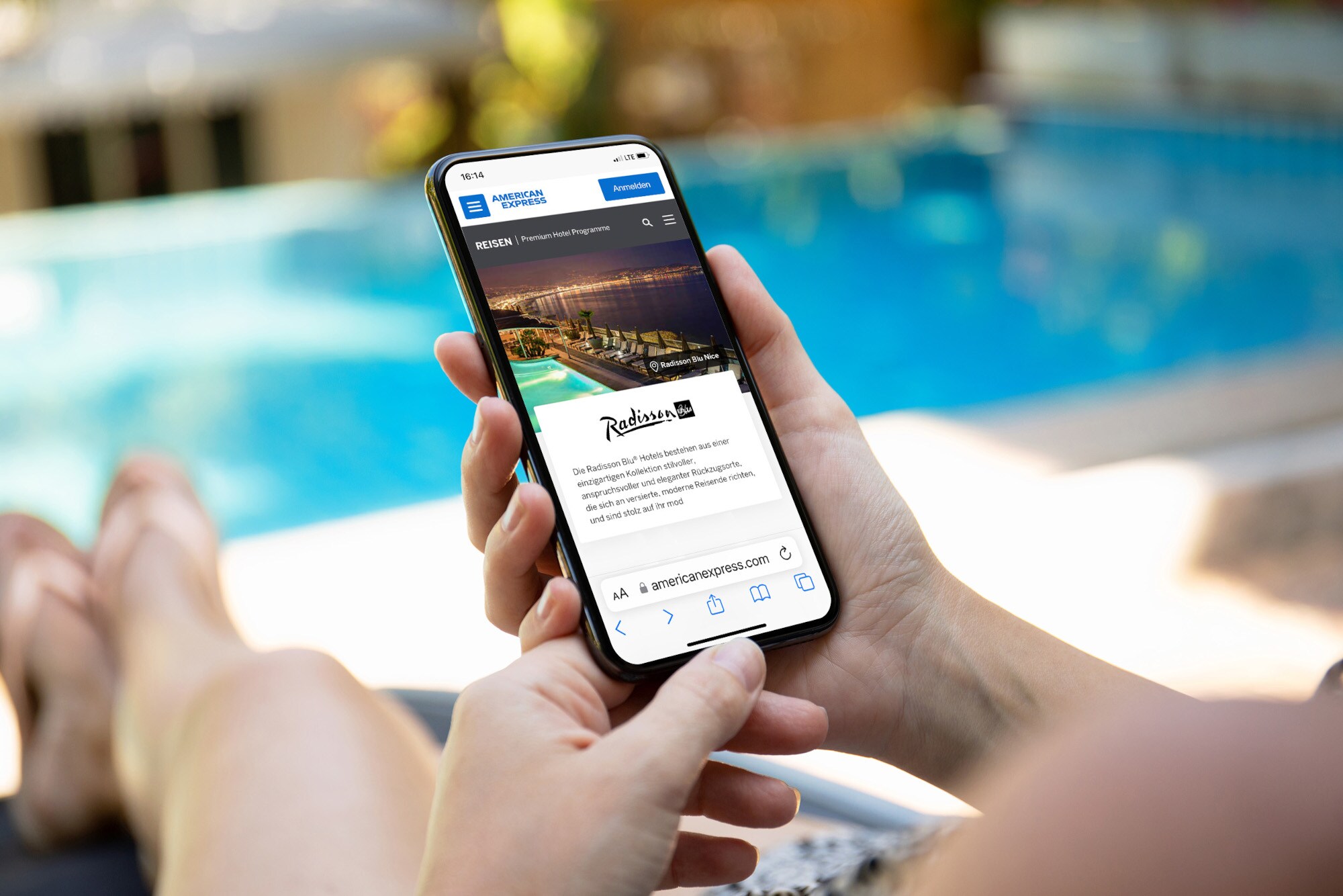 Eine Person auf einer Poolliege hält ein Smartphone mit dem American Express Online-Reiseportal auf dem Display in der Hand