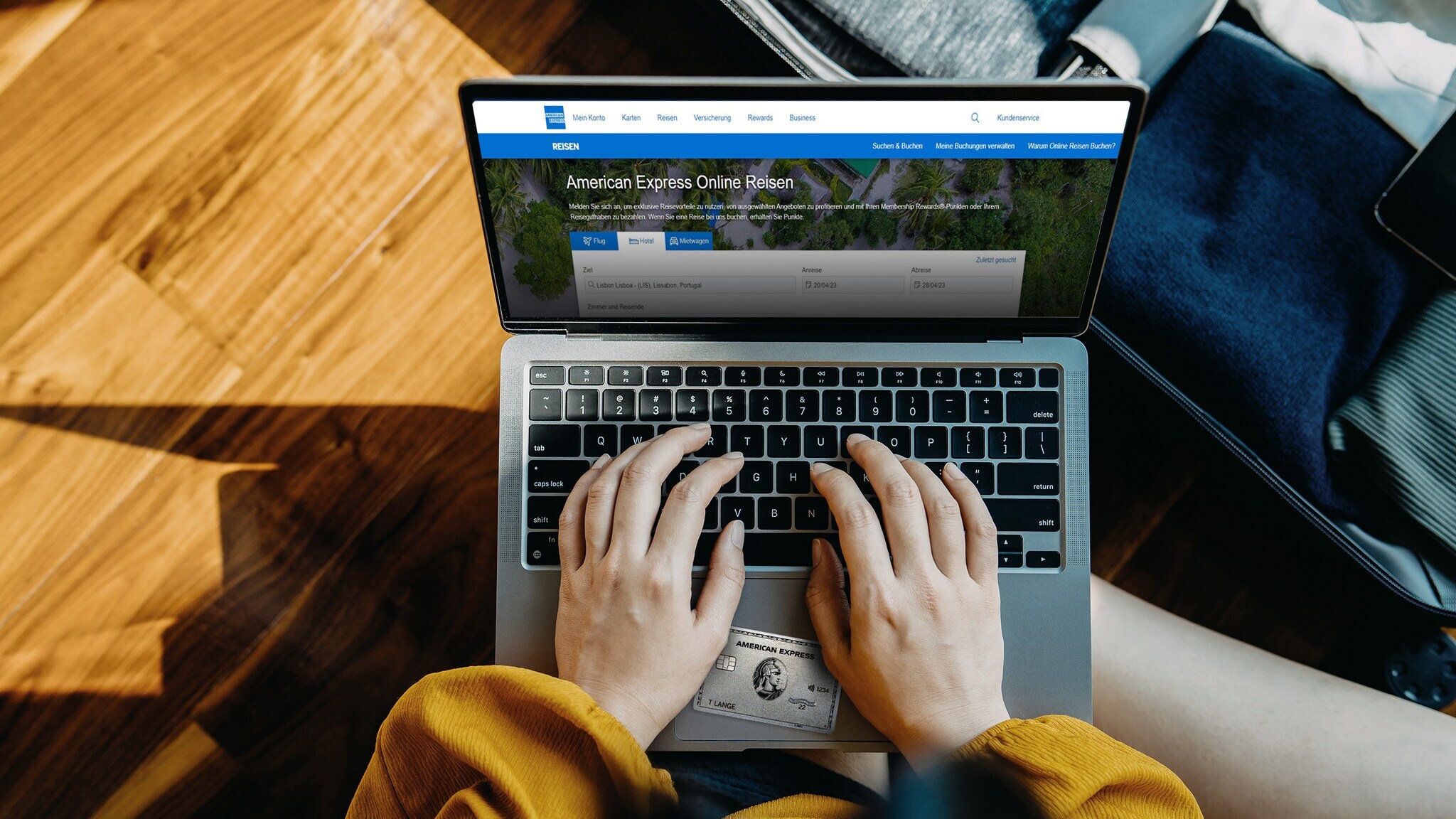 Aufsicht zweier Hände an einem Laptop bei der Buchung einer Reise über den American Express Online-Reiseservice mit einer Platinum Card.