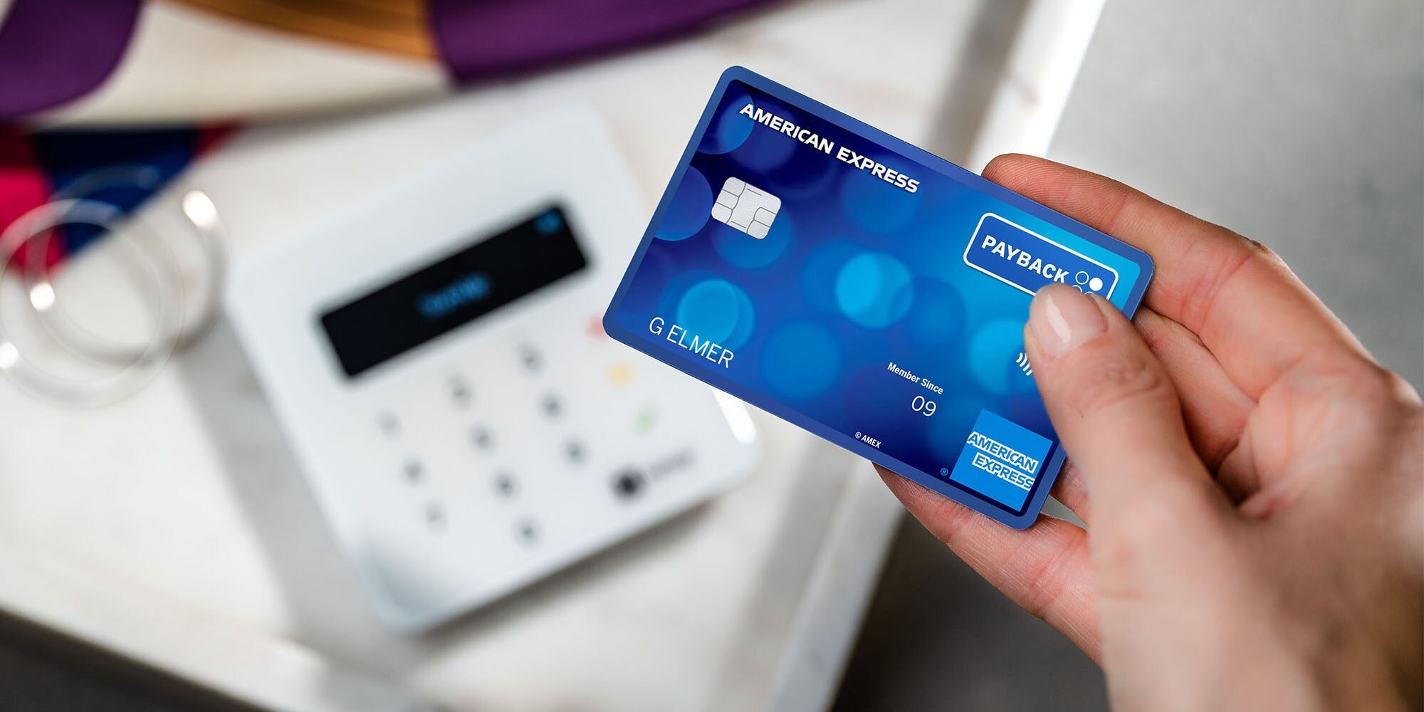 Kontaktlose Zahlung mit einer blauen Payback American Express Karte an einem Kartenlesegerät in einer Boutique. Kontaktlose Zahlung mit einer blauen Payback American Express Karte an einem Kartenlesegerät in einer Boutique.