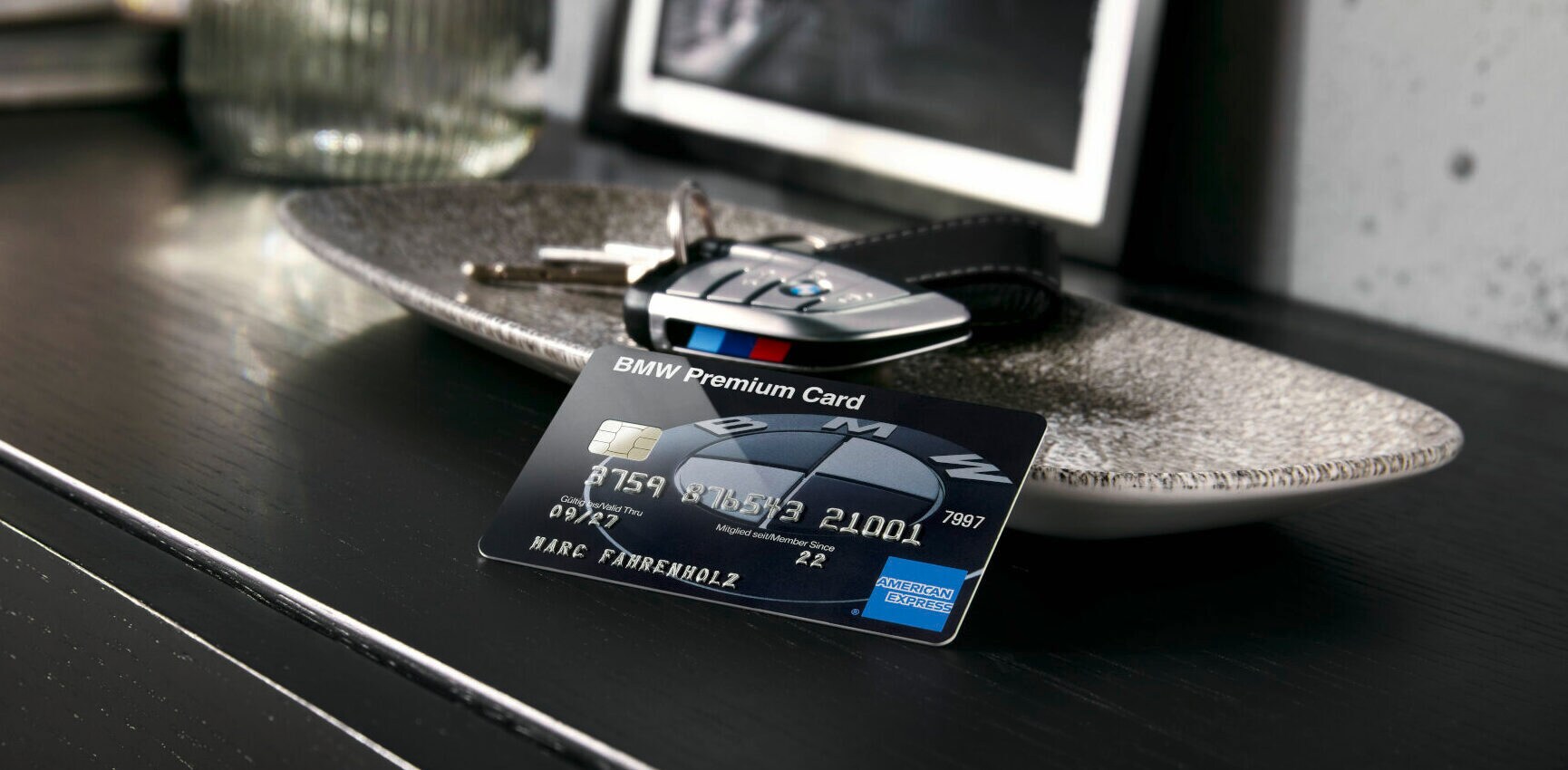 Auf einem Sideboard steht eine Schale, in der ein Autoschlüssel liegt, davor befindet sich die BMW Card Carbon.