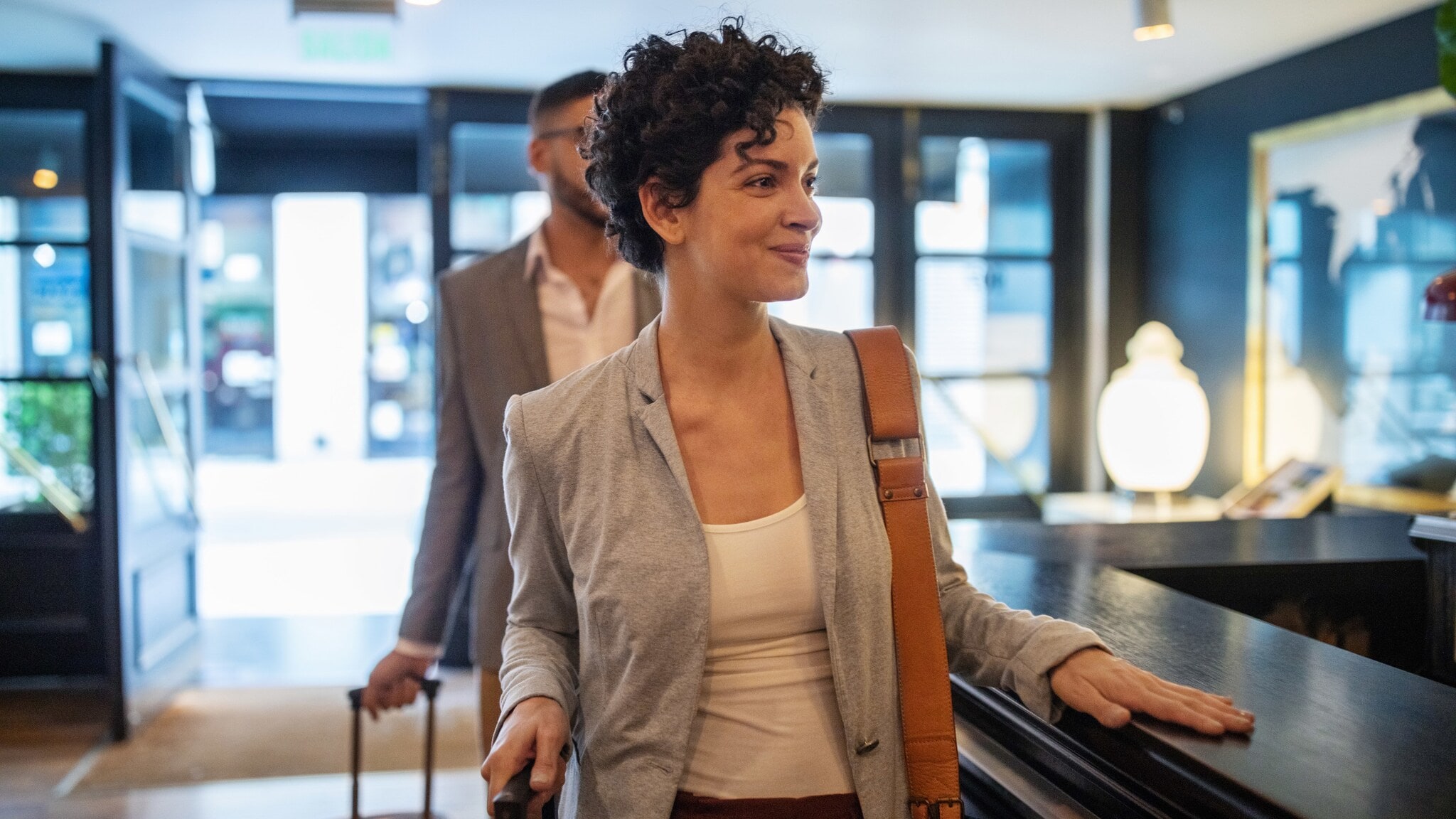 Eine Frau und ein Mann mit Rollkoffern an einer Hotelrezeption. Eine Frau und ein Mann mit Rollkoffern an einer Hotelrezeption.