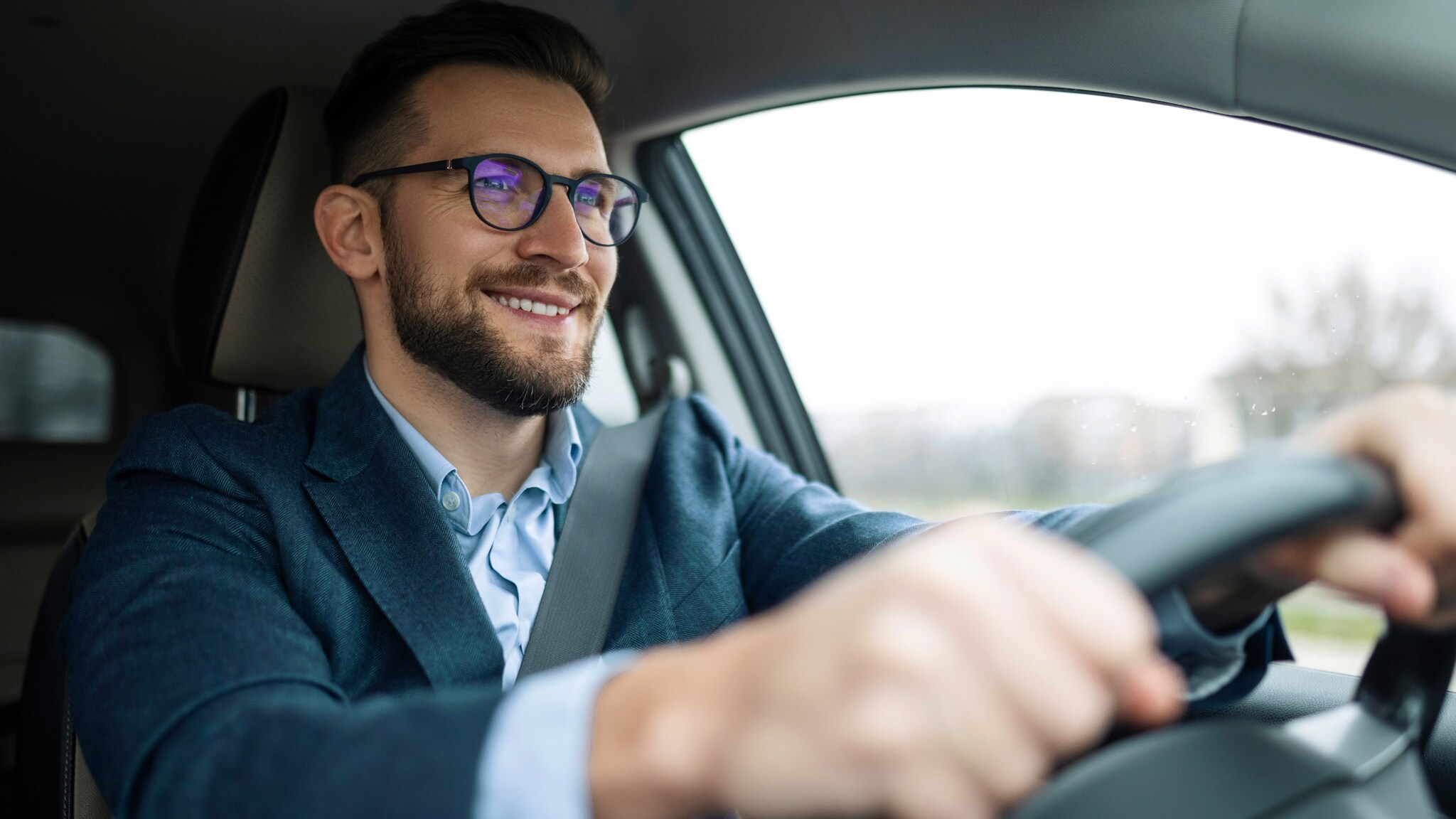 Ein Mann im Business-Outfit fährt lächelnd Auto. Ein Mann im Business-Outfit fährt lächelnd Auto.