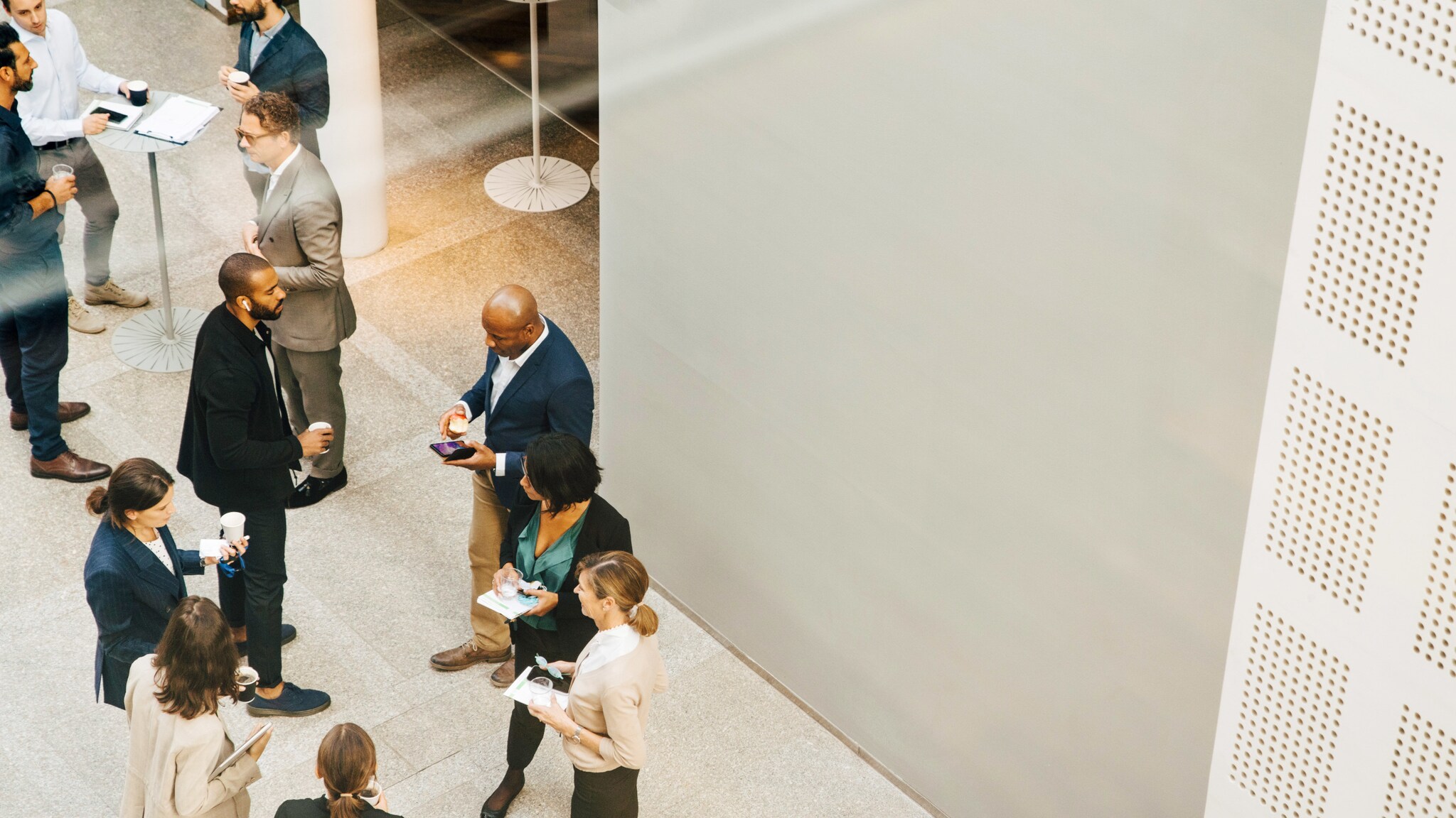 Eine Gruppe Geschäftsleute diskutiert rund um Stehtische.