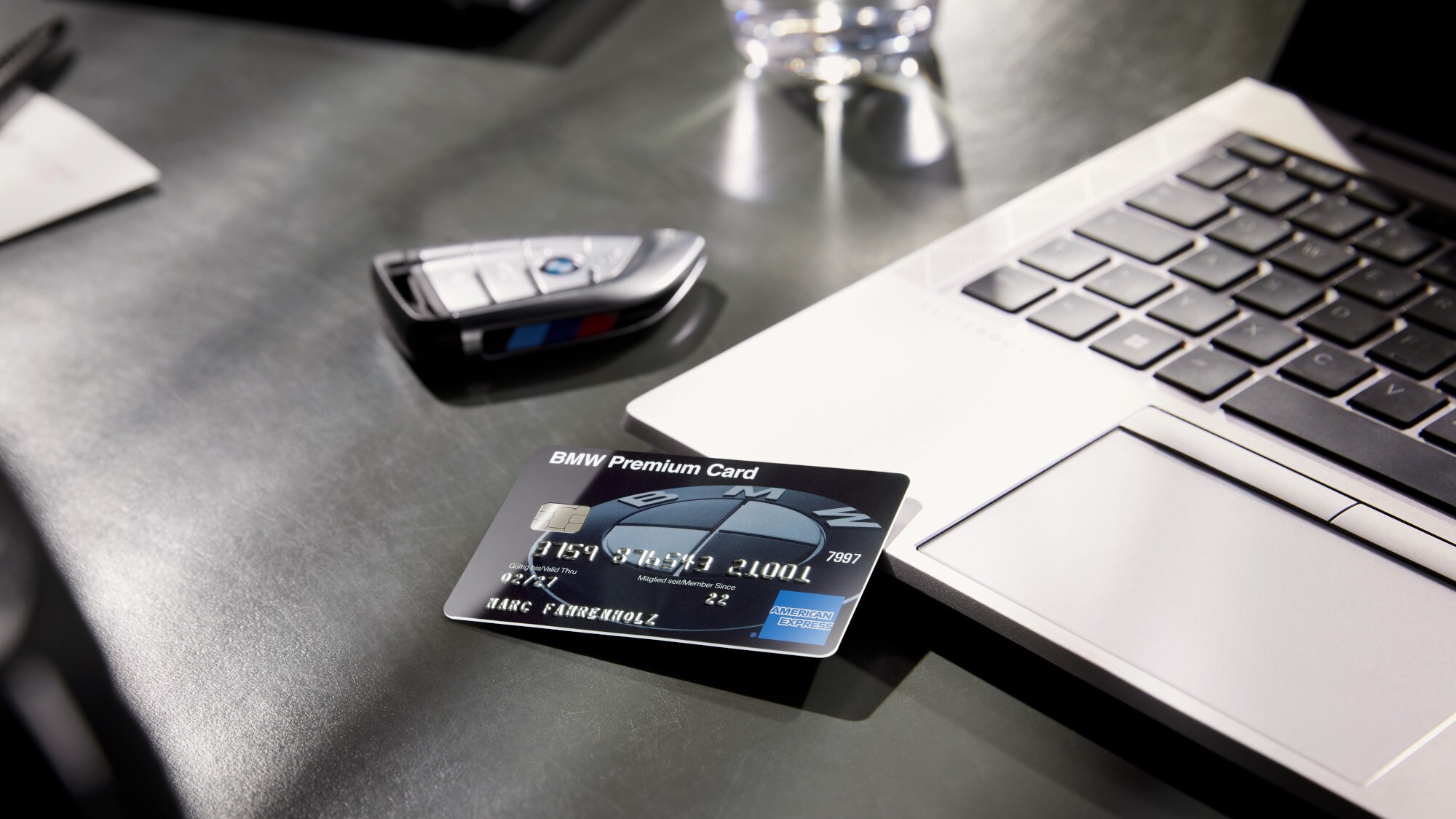 Eine BMW Premium Kreditkarte liegt auf einem Schreibtisch auf einem Laptop neben einem BMW Autoschlüssel. Eine BMW Premium Kreditkarte liegt auf einem Schreibtisch auf einem Laptop neben einem BMW Autoschlüssel.