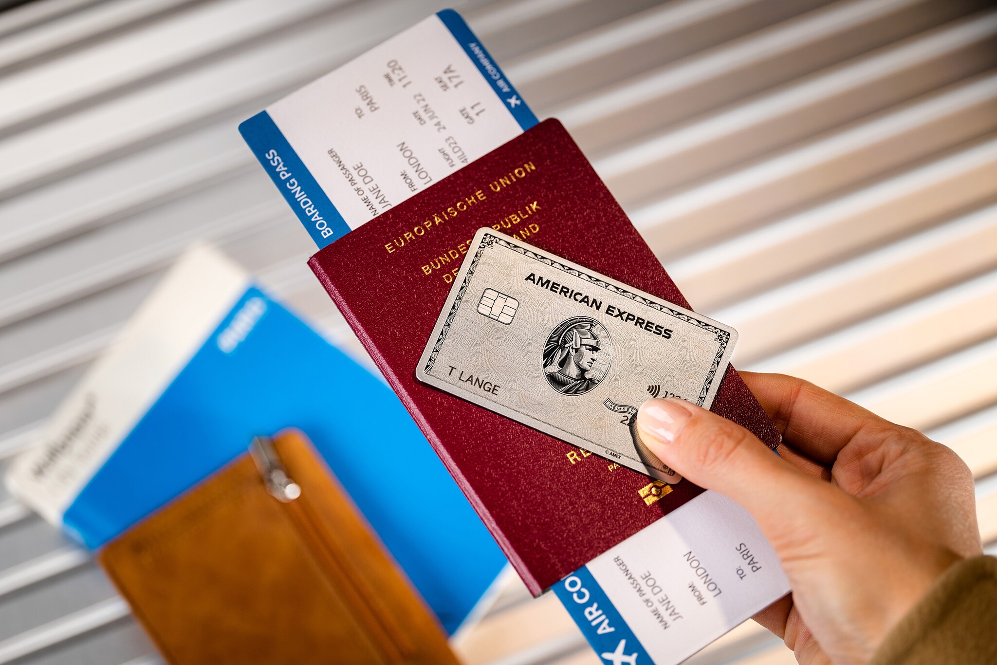 Eine Amex Platinum Card zusammen mit Reiseunterlagen in einer Hand. Eine American Express Platinum Card zusammen mit Reiseunterlagen in einer Hand.