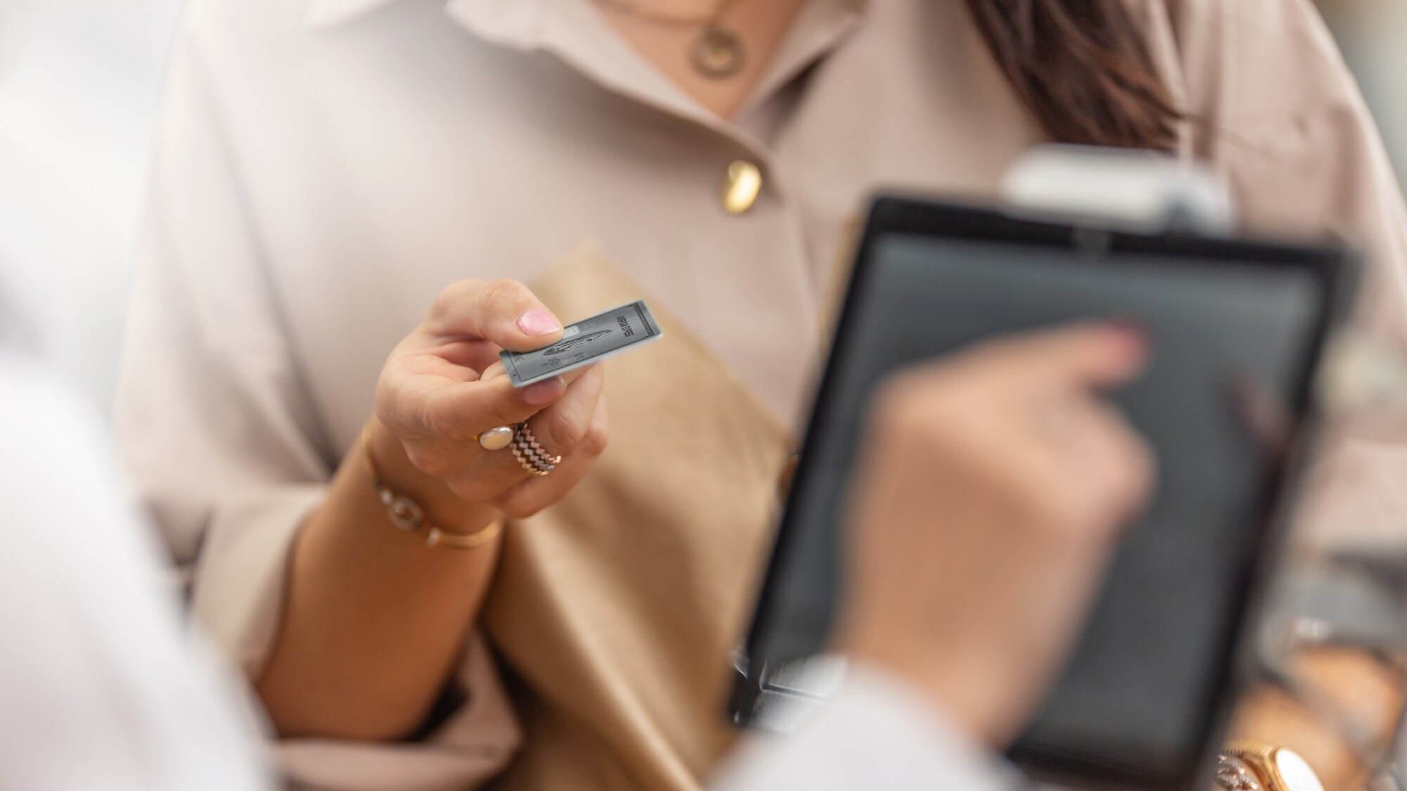 Nahaufnahme einer Kundin, die an der Kasse eines Geschäfts mit einer silbernen Kreditkarte aus Metall in ihrer Hand bezahlt
