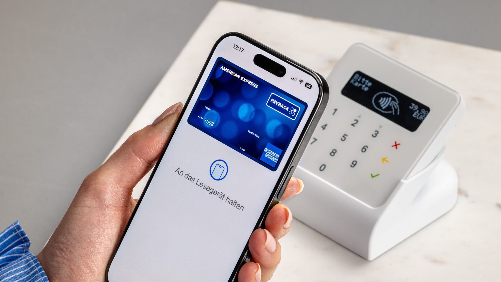 Eine Person hält ihr Smartphone mit der hinterlegten American Express PAYBACK Kreditkarte vor ein Kartenlesegerät. Eine Person hält ihr Smartphone mit der hinterlegten American Express PAYBACK Kreditkarte vor ein Kartenlesegerät.
