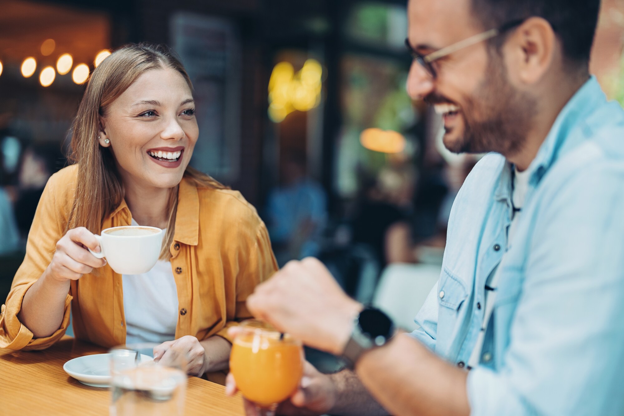 Ein lachendes Paar beim Kaffee trinken an einem Tisch in einem Restaurant.
