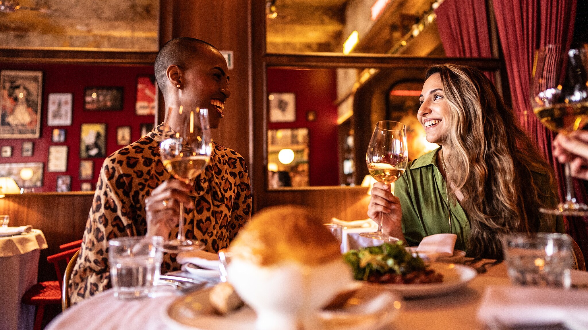 Zwei gut gelaunte Frauen an einem Tisch beim Dinner in einem Restaurant.