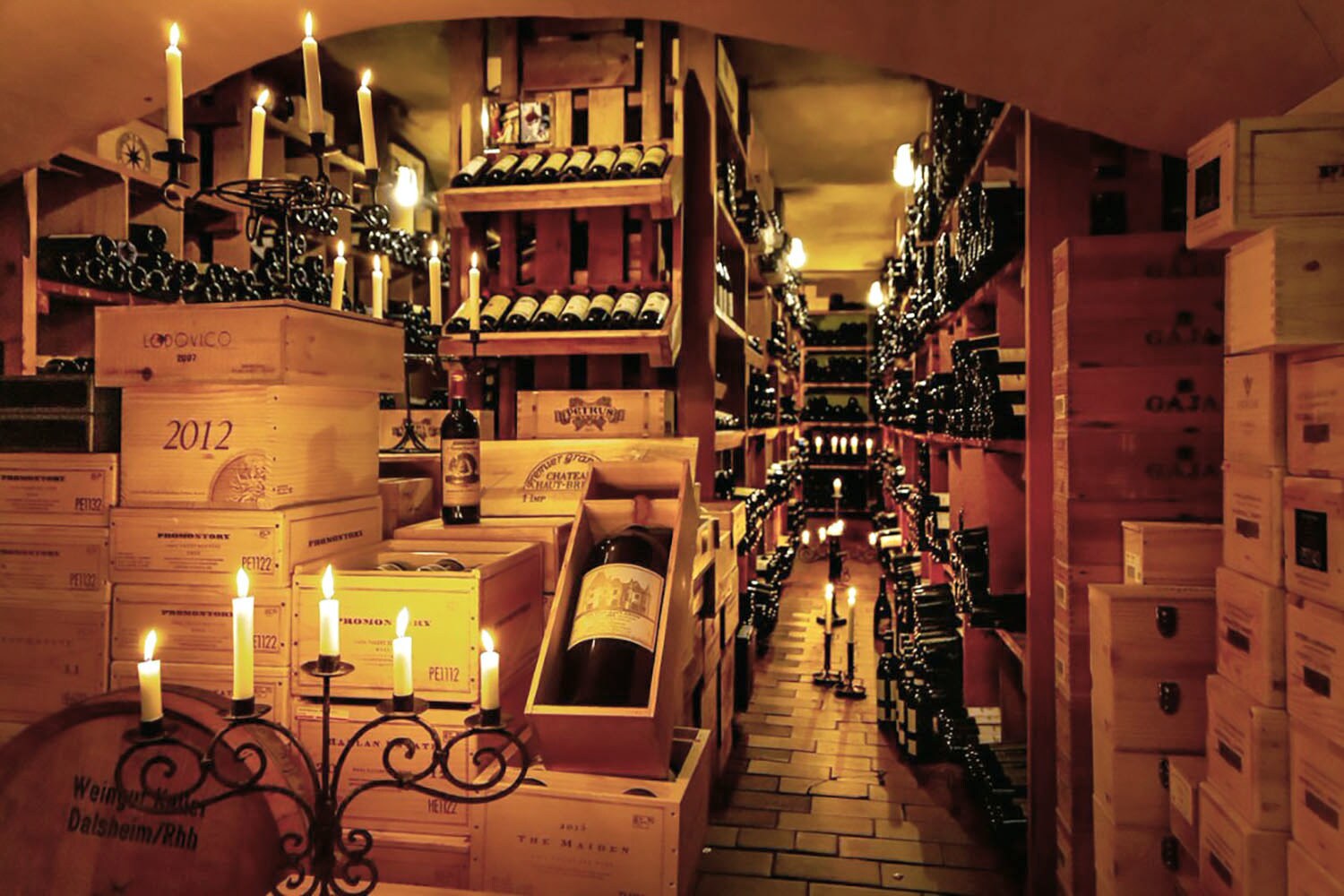 Weinkeller mit Weinflaschen in Regalen und Holzkisten bei Kerzenschein.