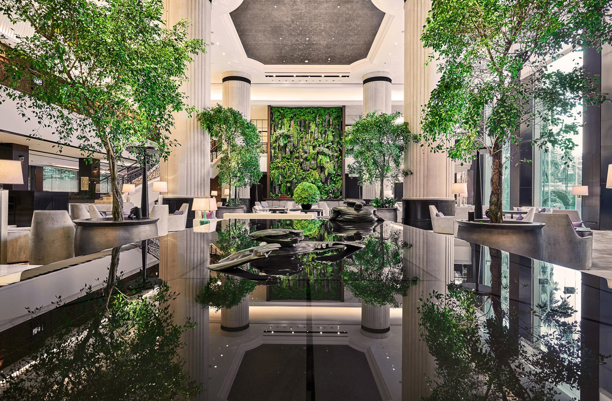 Begrünte Hotelrezeption in einer luxuriösen Empfangshalle mit Marmorsäulen und Bäumen. Begrünte Hotelrezeption in einer luxuriösen Empfangshalle mit Marmorsäulen und Bäumen.