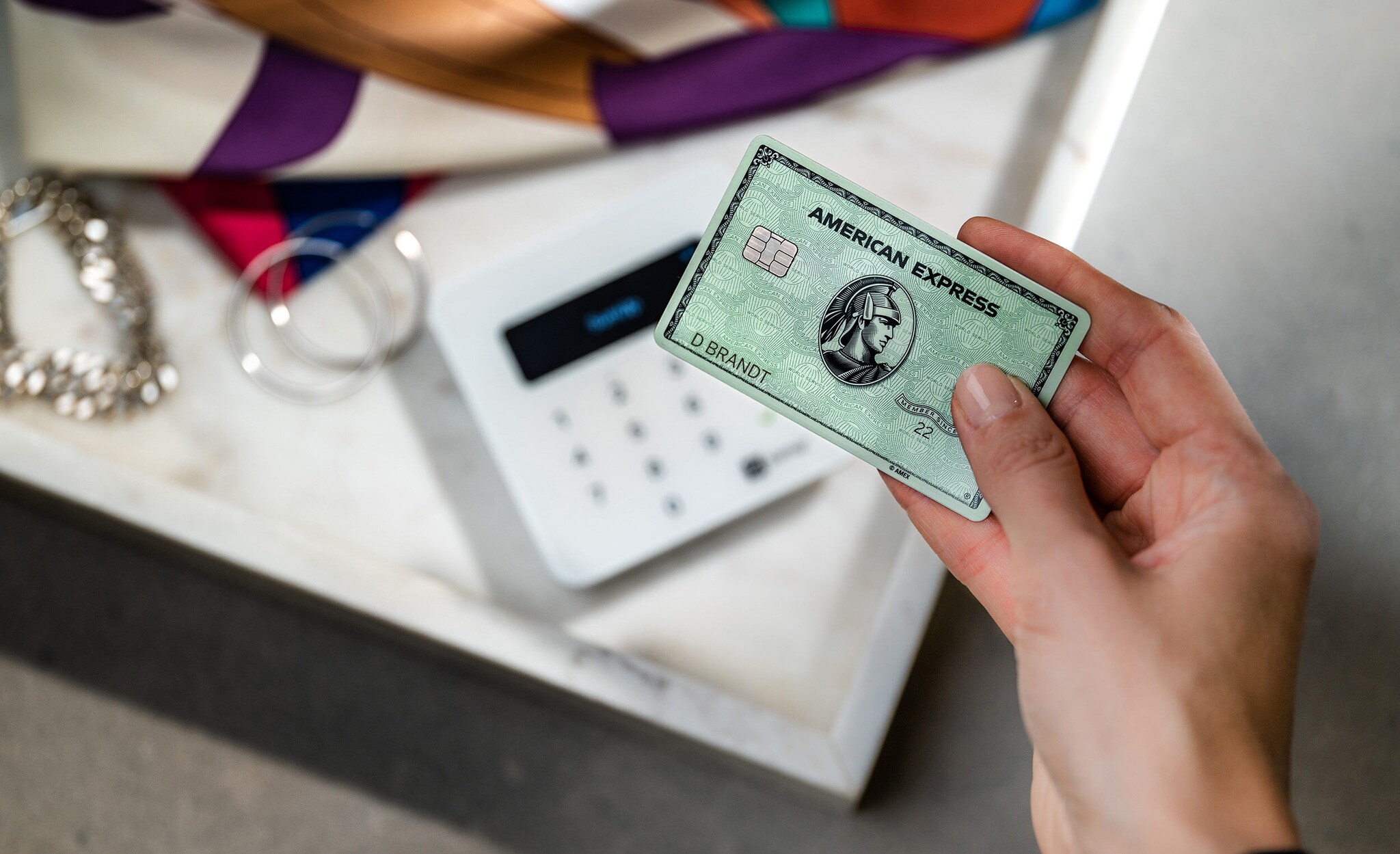 Bezahlung mit der Amex Card an einem Kartenlesegerät in einer Boutique.