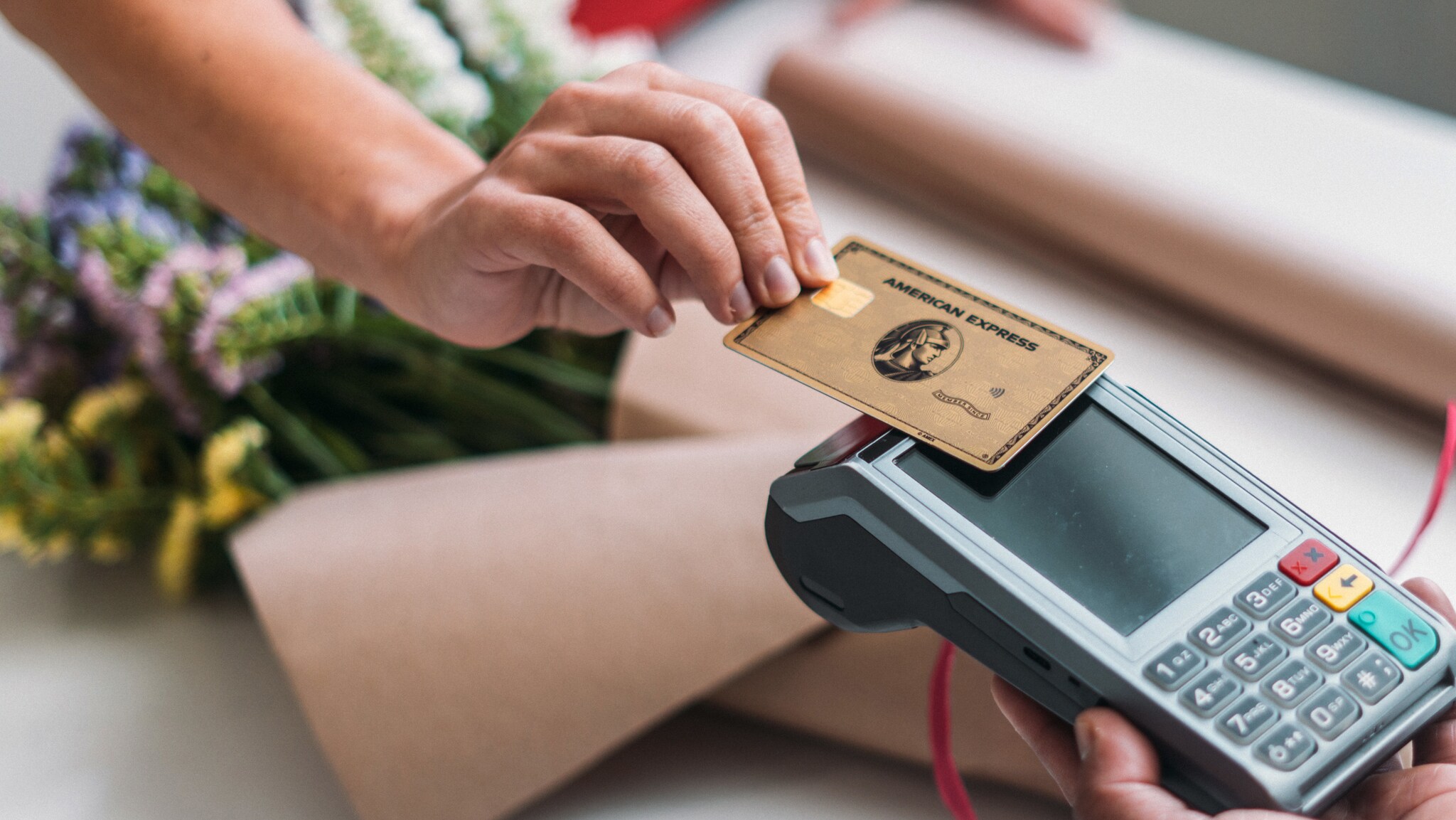 Kontaktlose Zahlung mit einer goldenen American Express Kreditkarte an einem Kartenlesegerät. Kontaktlose Zahlung mit einer goldenen American Express Kreditkarte an einem Kartenlesegerät.