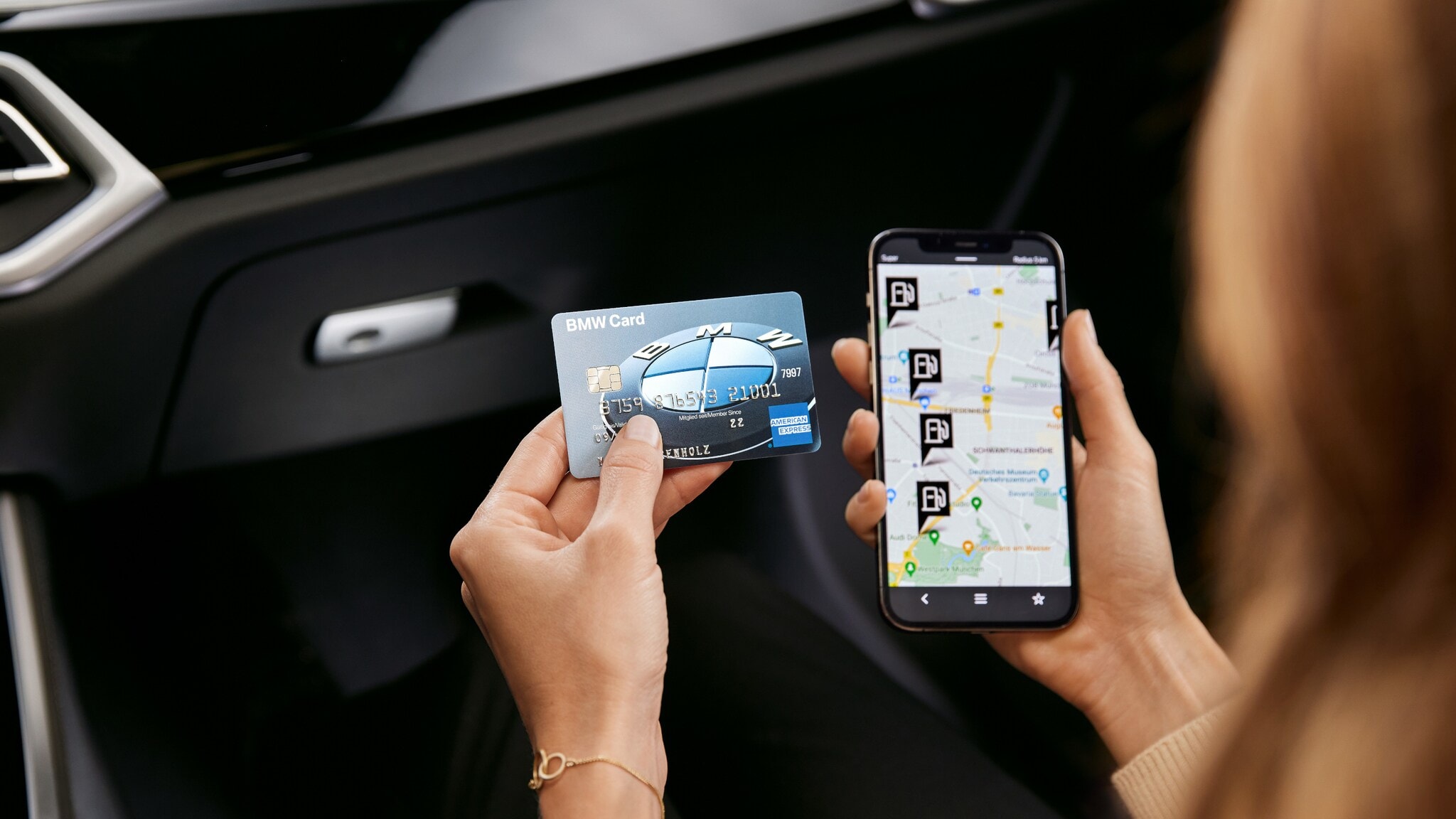 Eine BMW Card von American Express neben einem Smartphone mit Tankstellen-Icons auf einer Straßenkarte auf dem Display, gehalten von einer Person in einem Auto. Eine BMW Card von American Express neben einem Smartphone mit Tankstellen-Icons auf einer Straßenkarte auf dem Display, gehalten von einer Person in einem Auto.