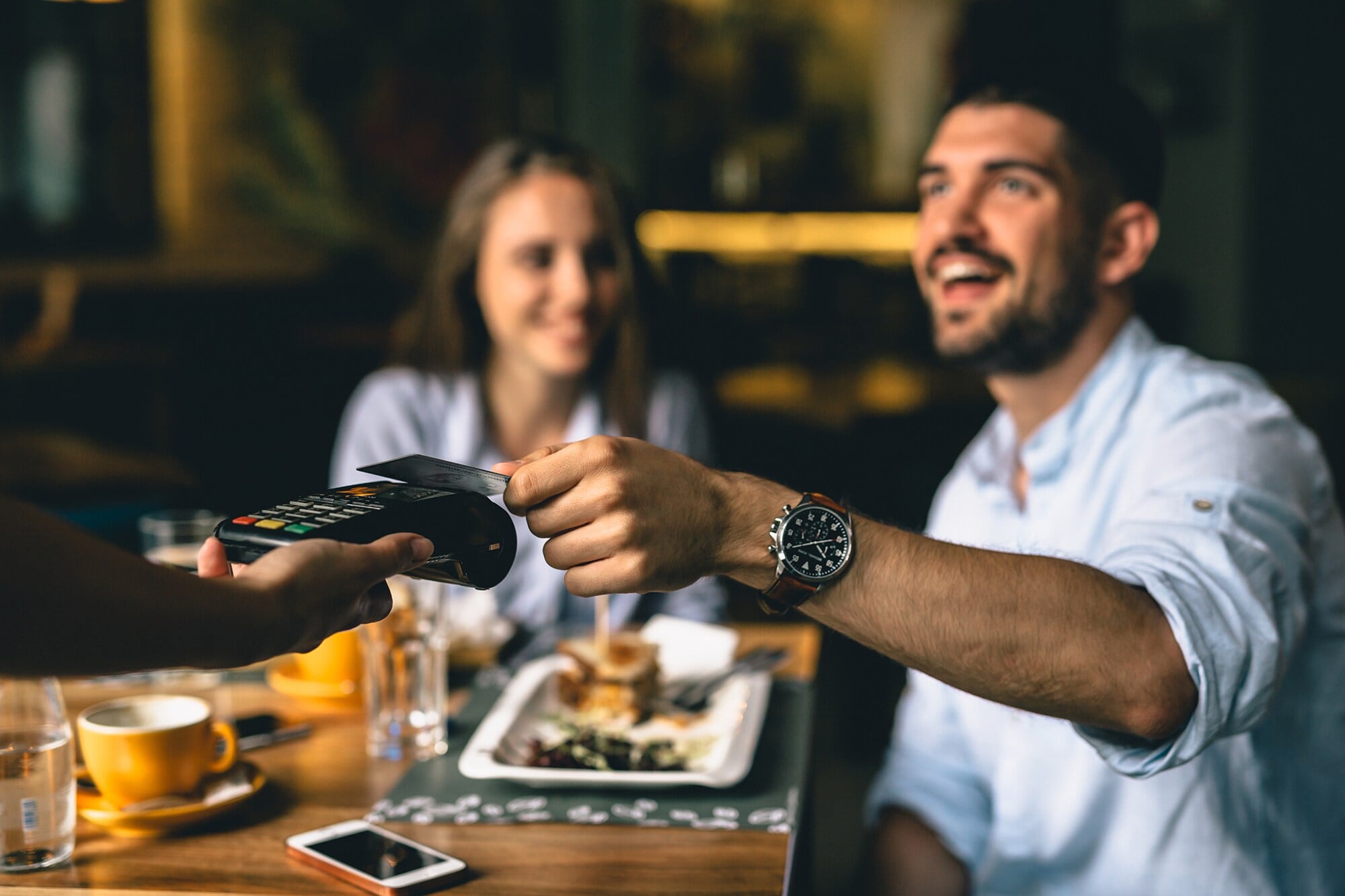 American Express Corporate Cards für Geschäftsreisende Ein junges Paar bezahlt im Restaurant mit Kreditkarte
