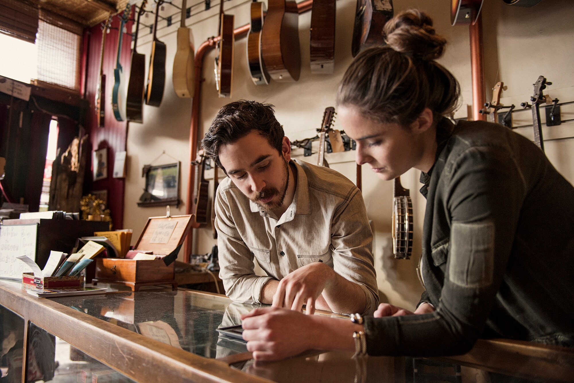 Die Inhaberin und der Inhaber eines Gitarrenshops schauen gemeinsam auf einen Taschenrechner.