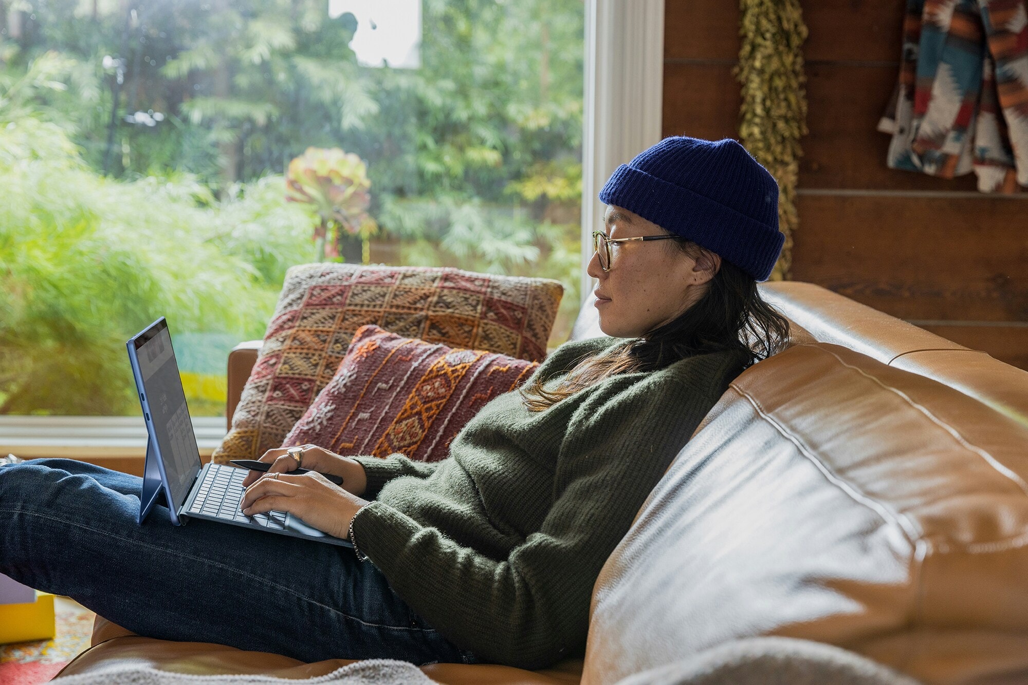 Amex Business Card bei PayPal hinterlegen & profitieren: So geht's Eine junge Frau sitzt gemütlich mit Laptop auf dem Sofa.