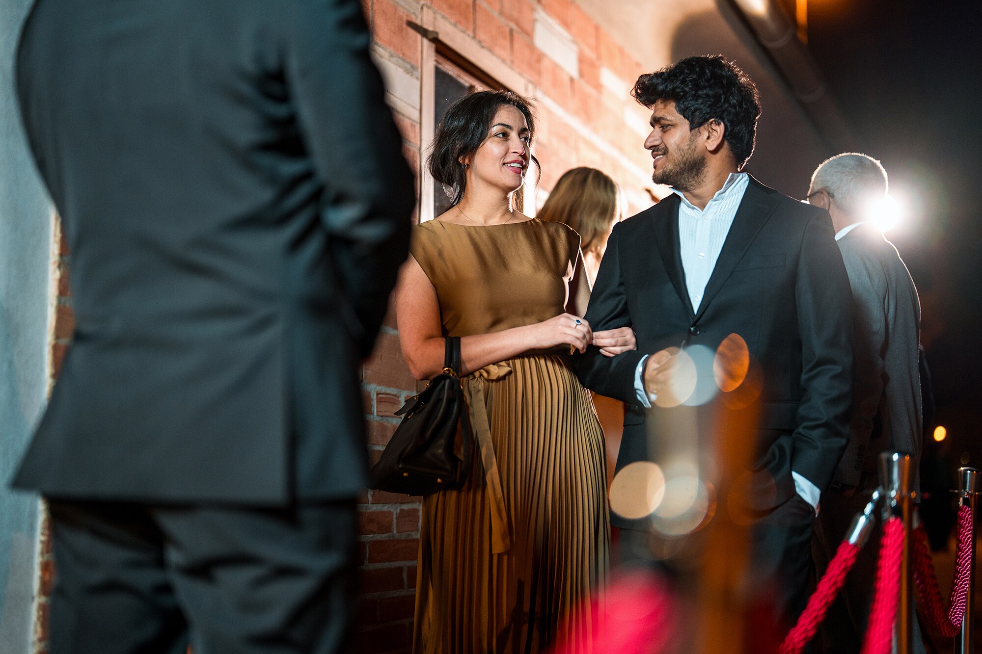 Ein glamouröses Paar steht vor dem Einlass eines exklusiven Events.