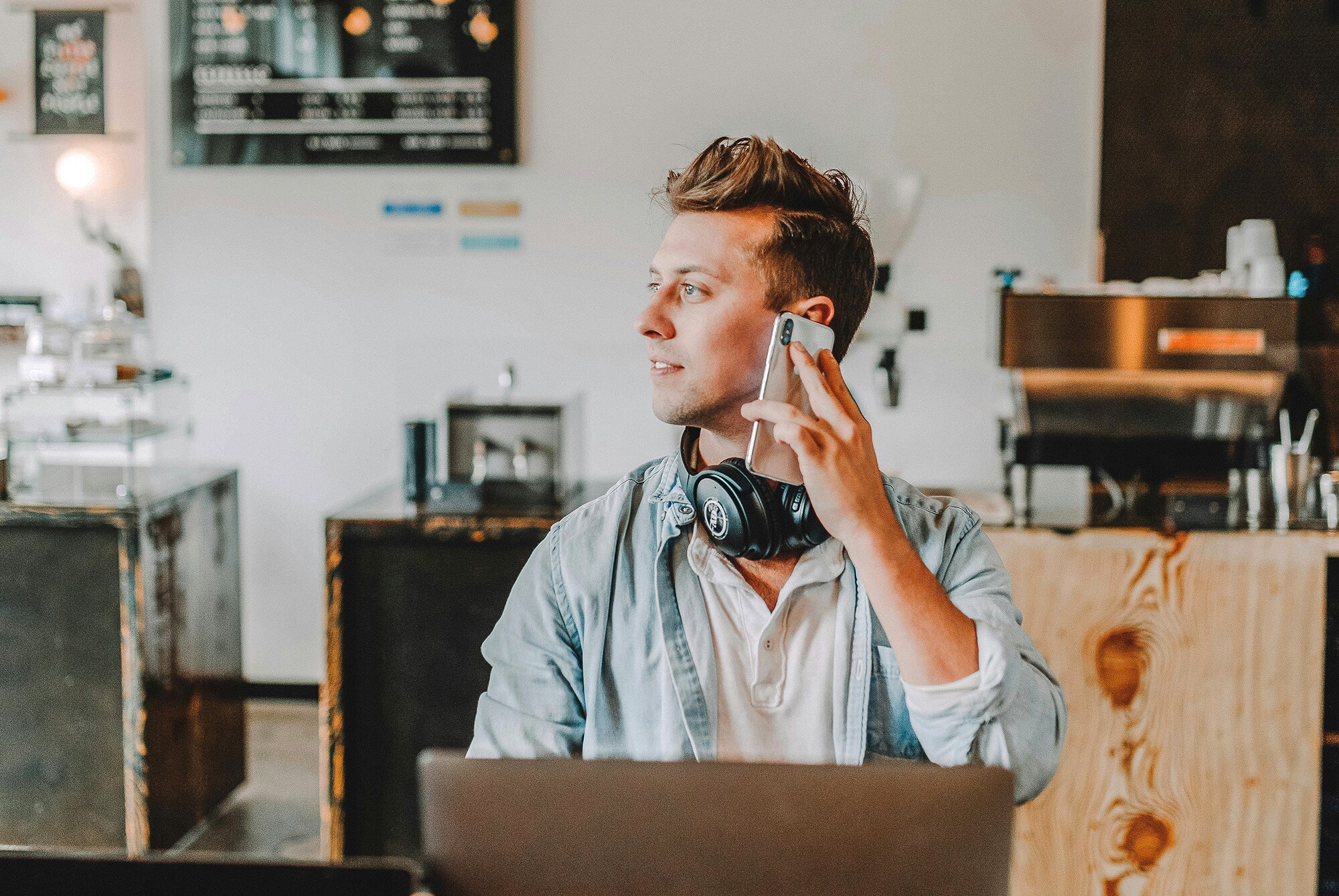 3 gute Gründe für American Express Firmenkreditkarten Ein junger Mann arbeitet im Café am Laptop und telefoniert.