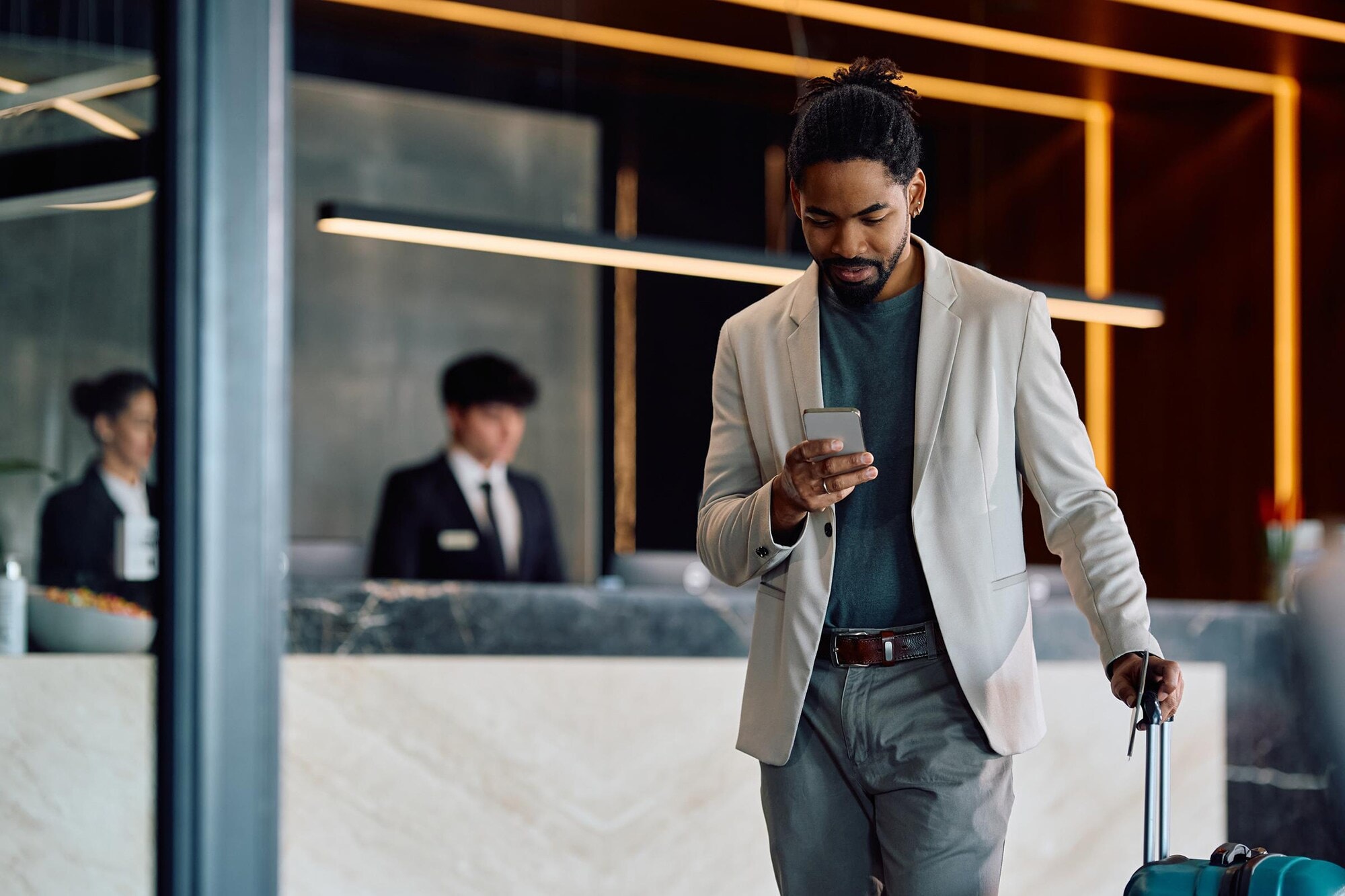 Upgrade für deine Geschäftsreise: American Express Fine Hotels + Resorts erleben Ein Geschäftsreisender kommt in der Hotellobby an.