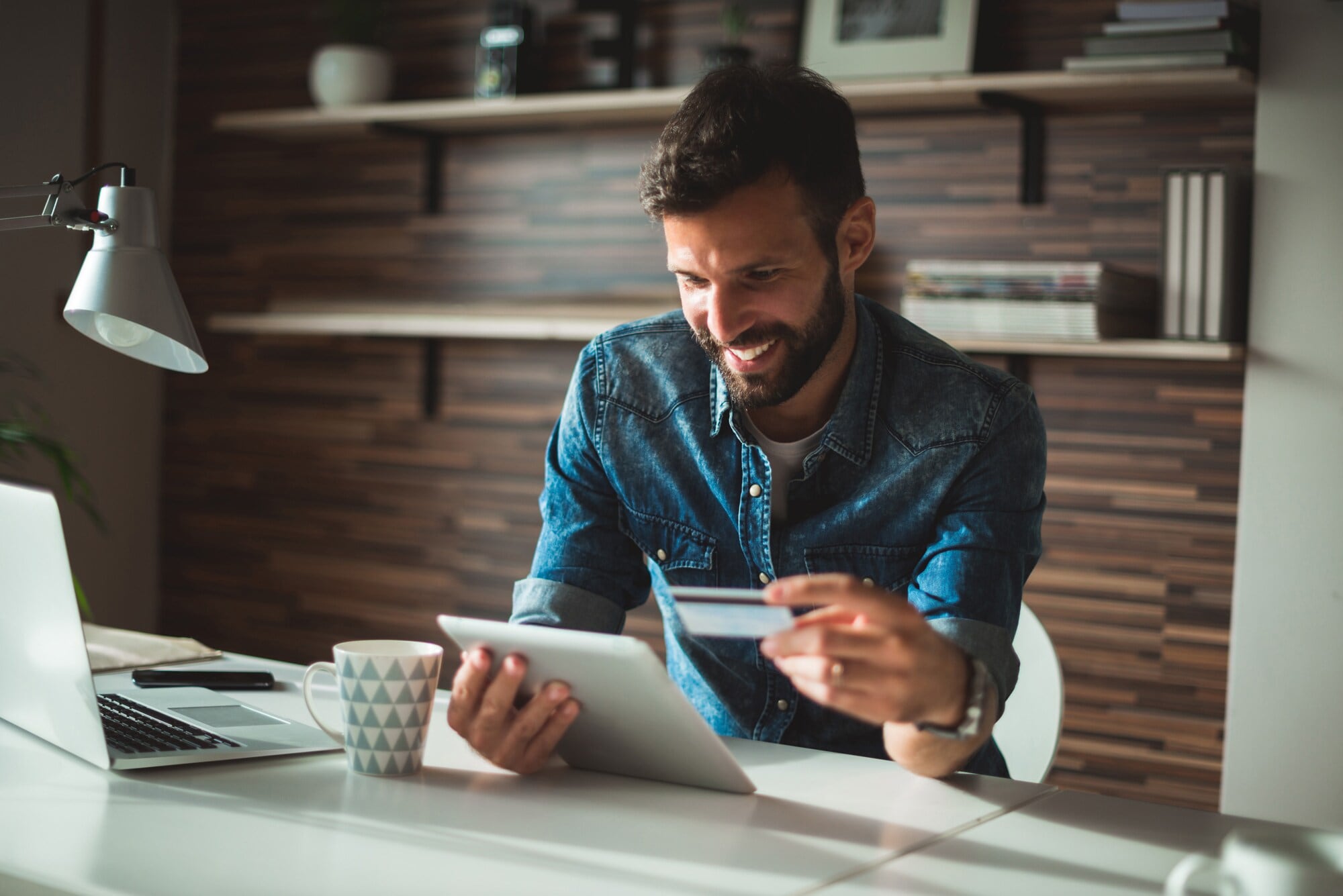 Eine junge Frau bezahlt kontaktlos mit ihrem Smartphone via Apple Pay in einem Café Ein lächelnder Mann am Schreibtisch beim Online-Banking