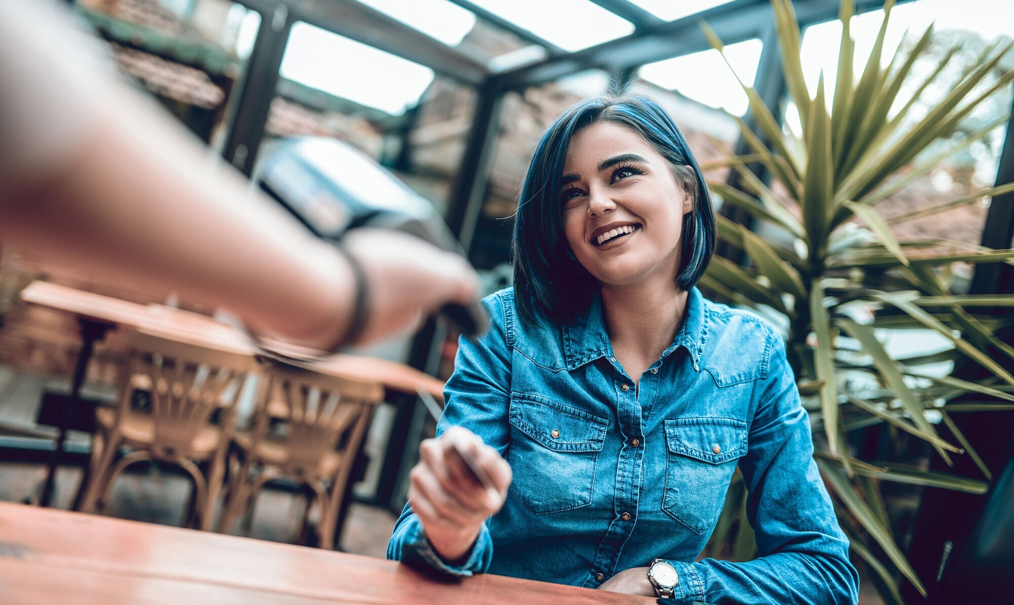 Eine junge Frau zahlt ihren Umsatz im Restaurant per Kreditkarte