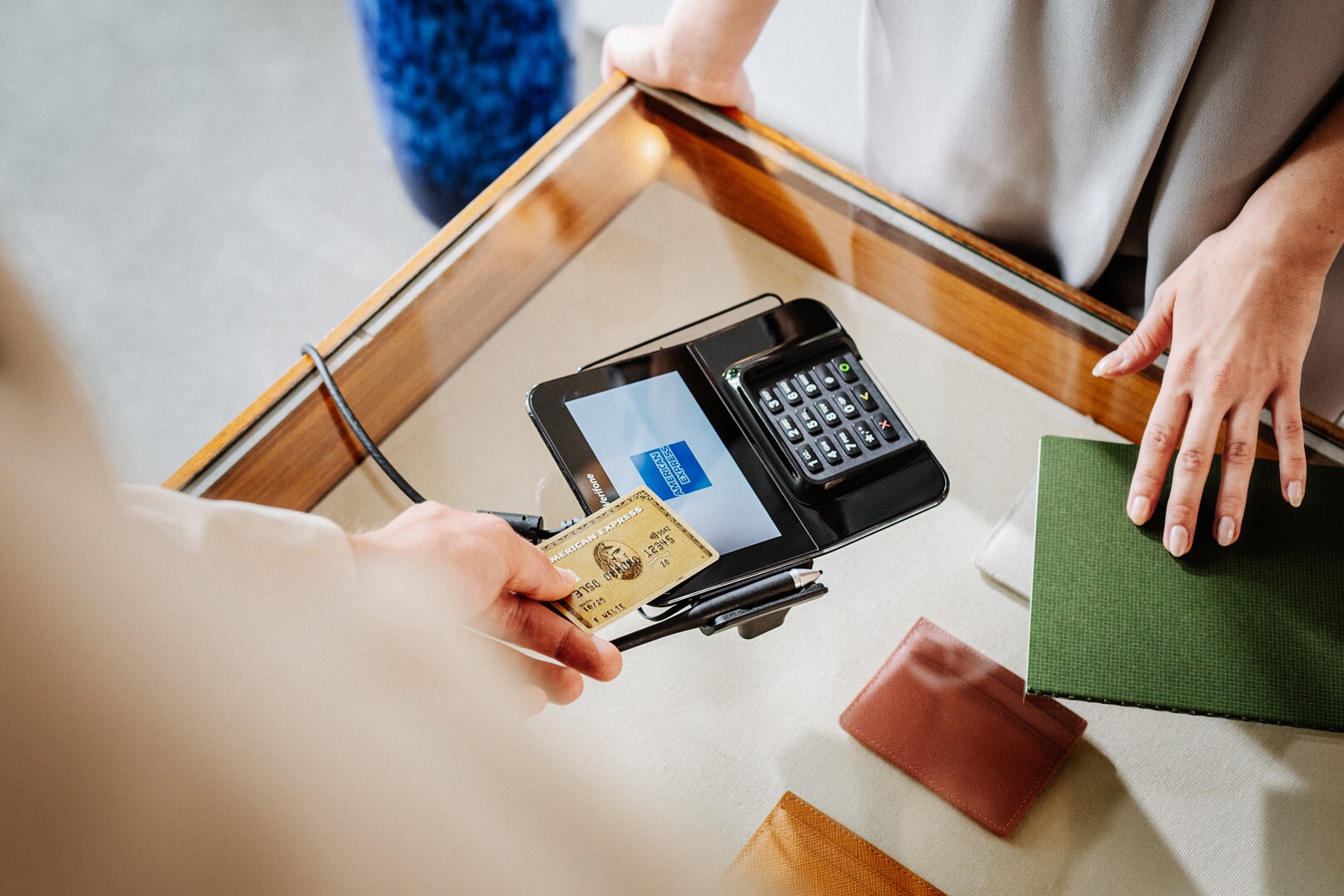 Eine Person zahlt in einer Amex Akzeptanzstelle kontaktlos mit Kreditkarte Eine Person zahlt in einer Amex Akzeptanzstelle kontaktlos mit Kreditkarte