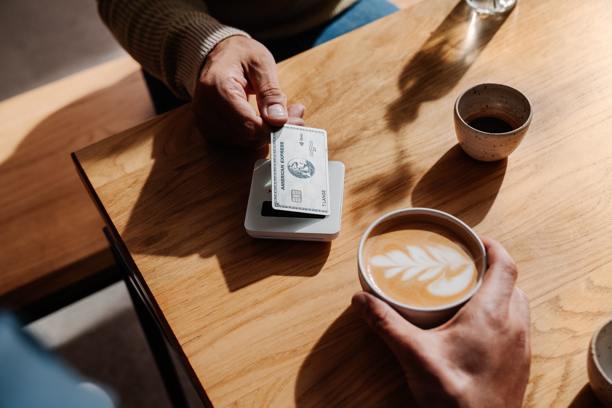 Kontaktlose Zahlung eines Cappuccinos mit einer silbernen Kreditkarte Kontaktlose Zahlung eines Cappuccinos mit einer silbernen Kreditkarte