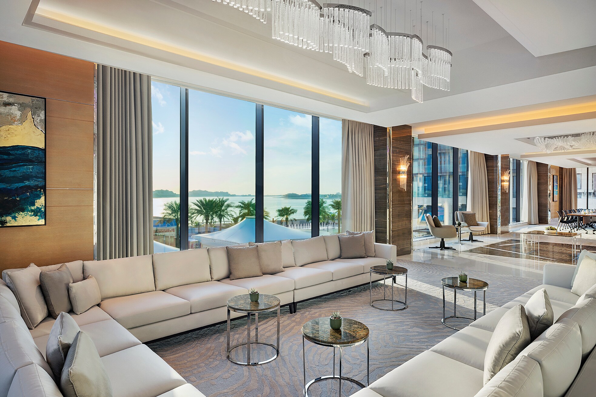 Elegantes Hotelfoyer mit hellen Polstermöbeln und bodentiefen Panoramafenstern mit Blick aufs Meer