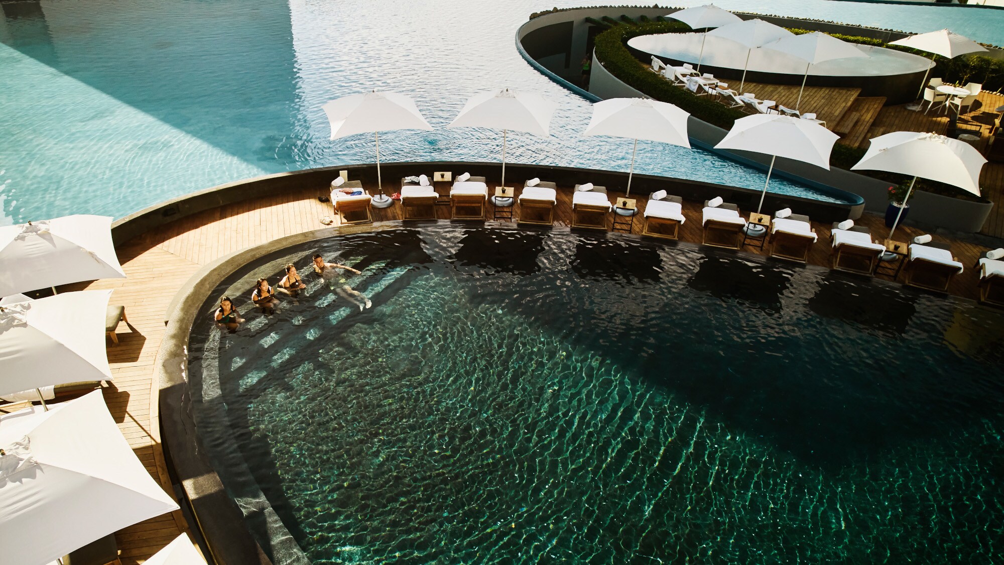 Aufsicht einer modernen Poollandschaft in einer exklusiven Hotelanlage mit Personen im Wasser. Aufsicht einer modernen Poollandschaft in einer exklusiven Hotelanlage mit Personen im Wasser.