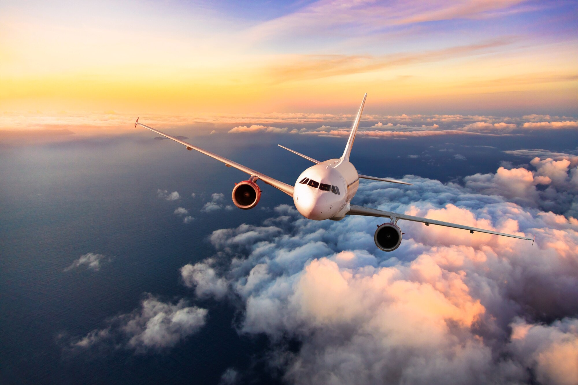 Ein Flugzeug fliegt über den Wolken bei Sonnenuntergang. Ein Flugzeug fliegt über den Wolken bei Sonnenuntergang.
