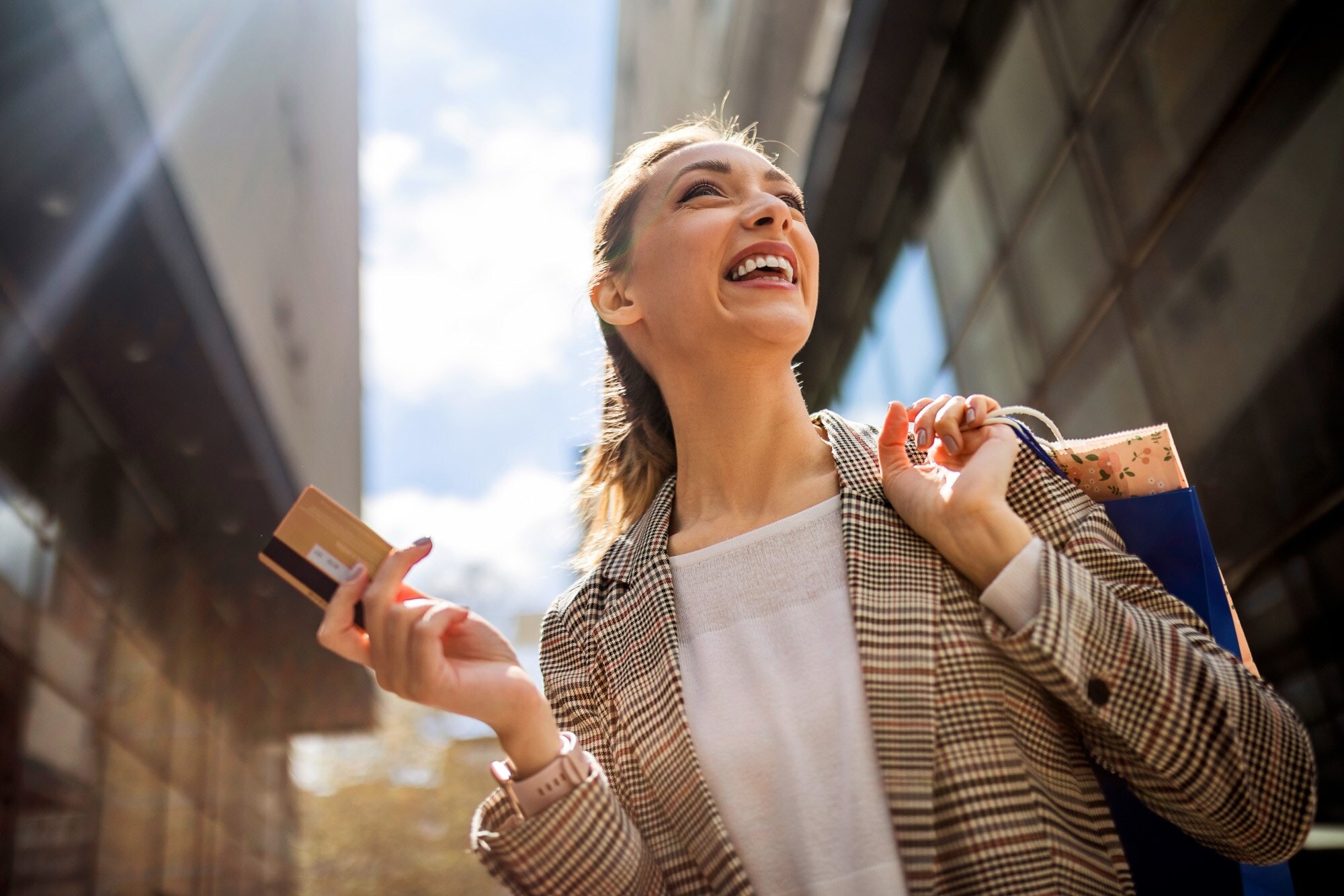Porträt einer jungen Frau mit Kreditkarte und Einkaufstauschen in den Händen beim Einkaufen in der Stadt